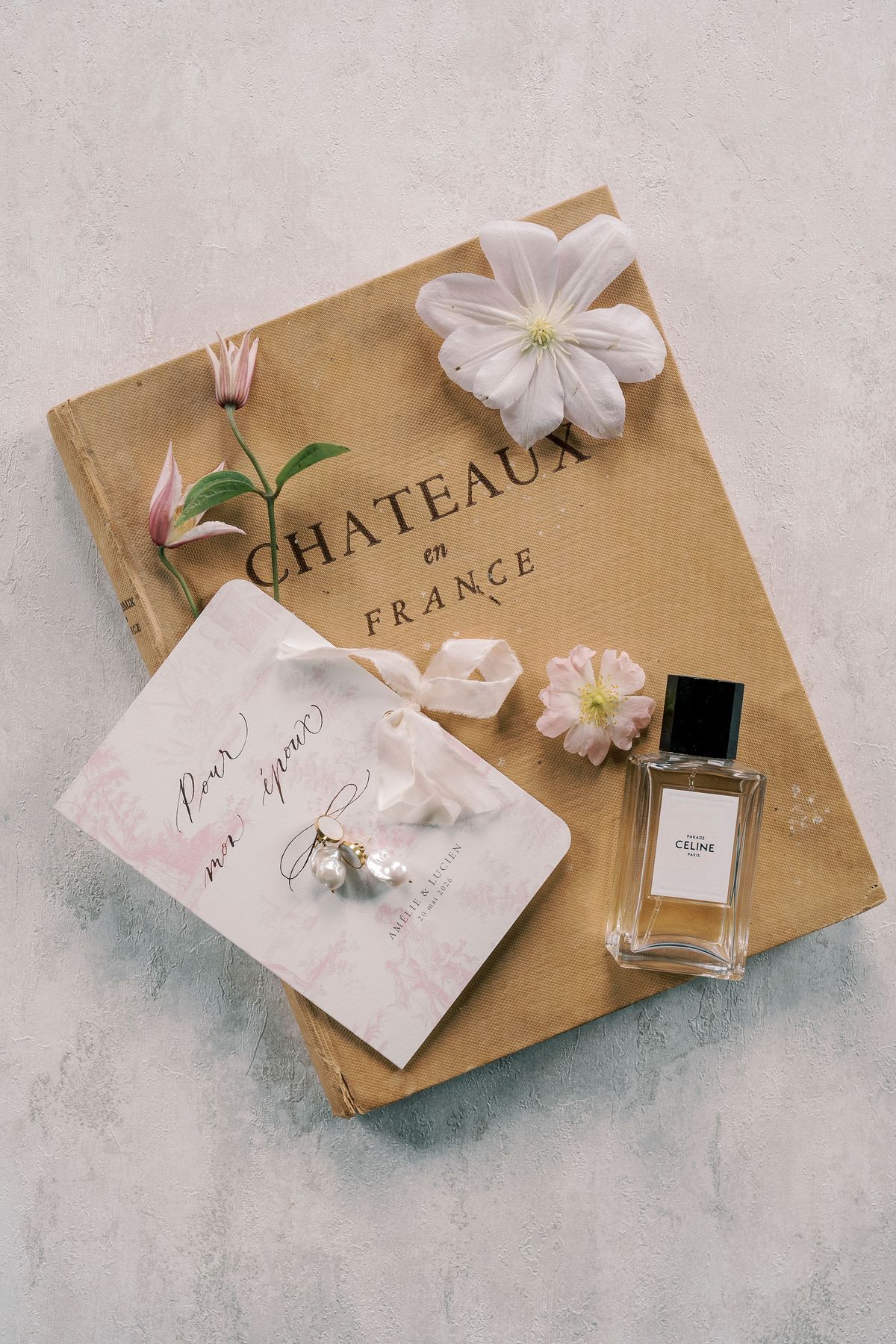 Flat lay of a Châteaux en France book, a ring box, a perfume bottle and flowers