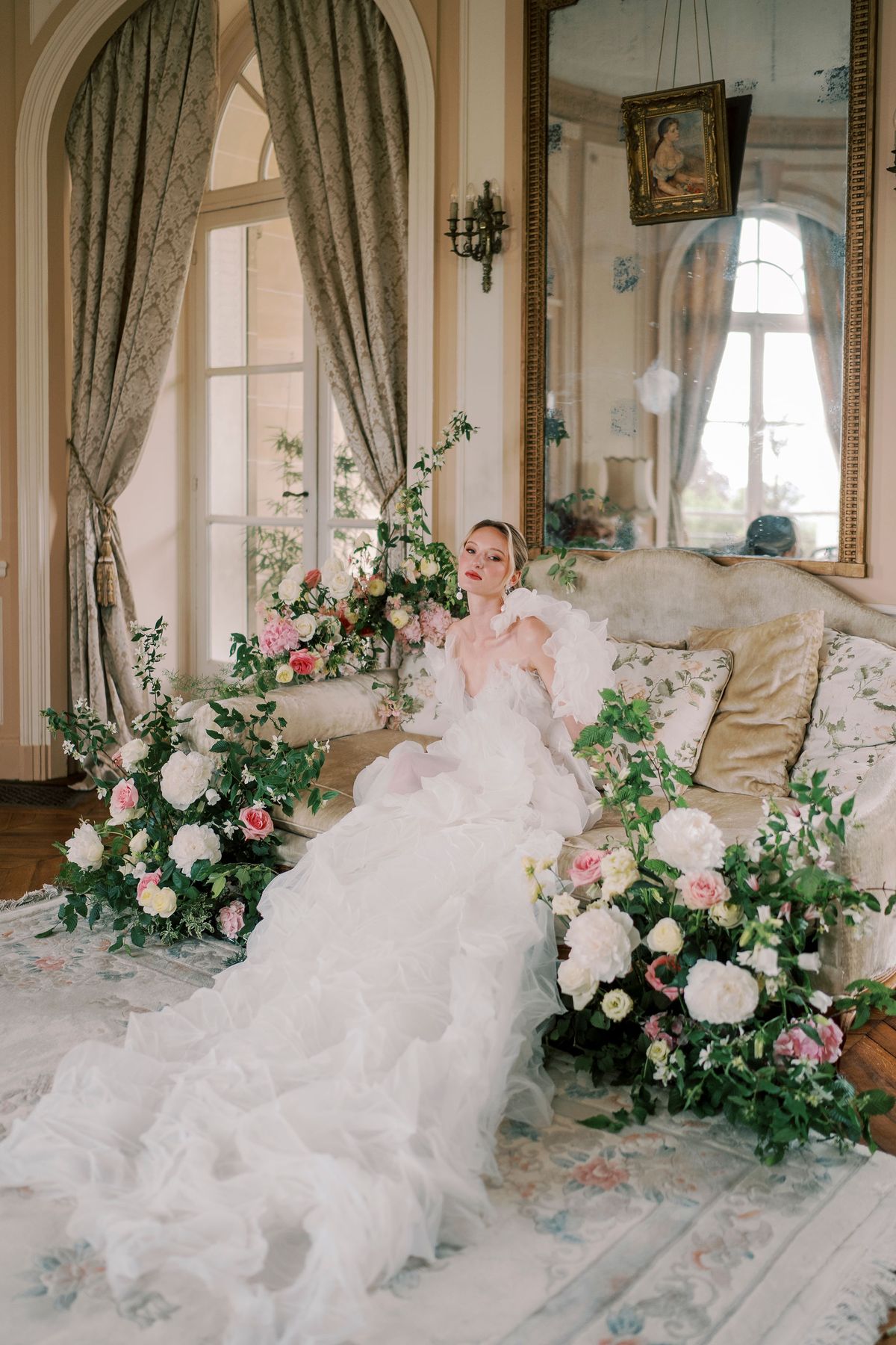 Amélie reclining on a pale sofa in a gilded salon, her organza gown spread around her
