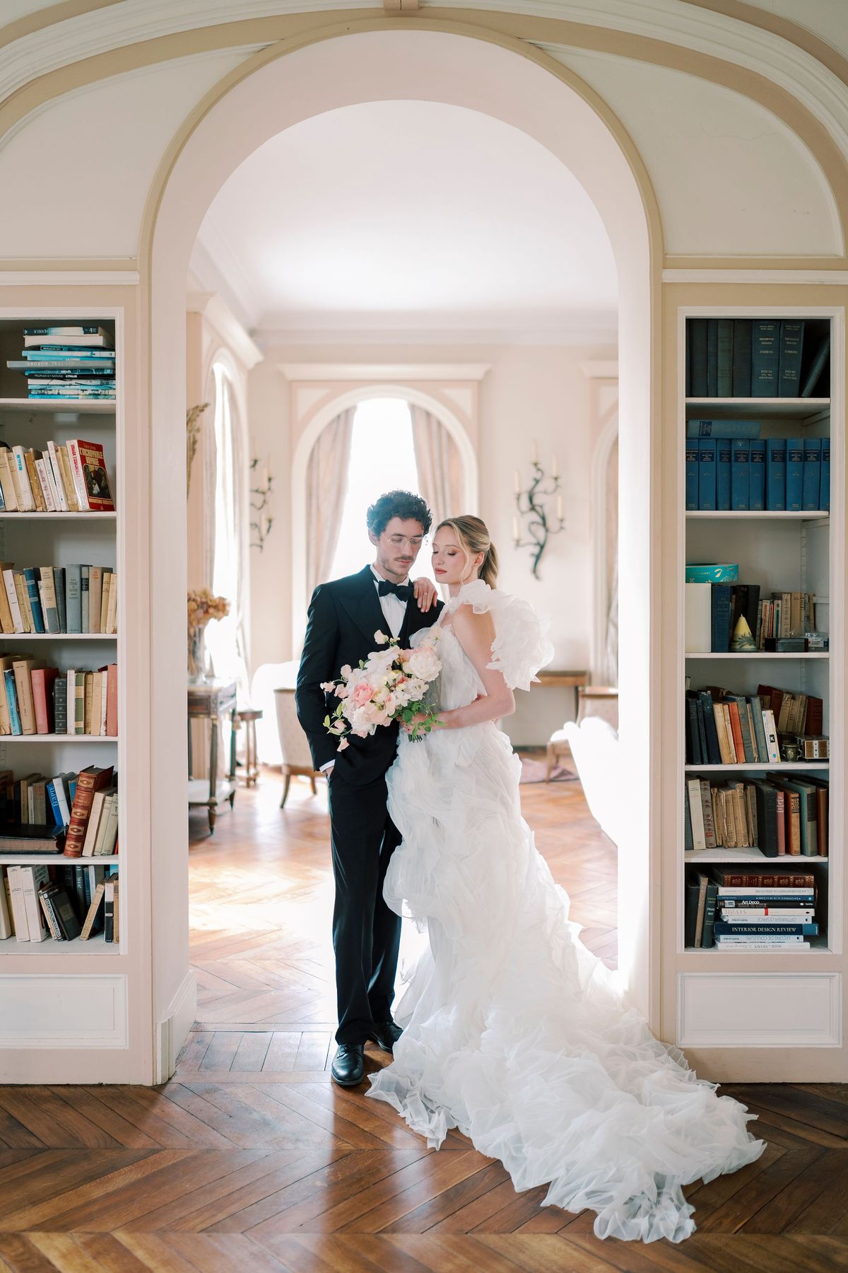 Amélie and Lucien in an arched doorway flanked by bookshelves at Château du Prieuré
