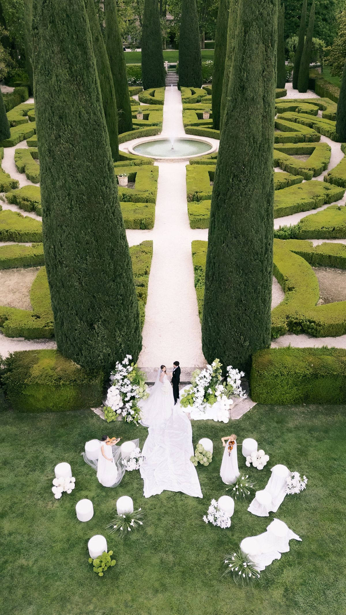 Aerial view down the cypress avenue to the ceremony setting and the bride's train at Château de Sannes, Provence