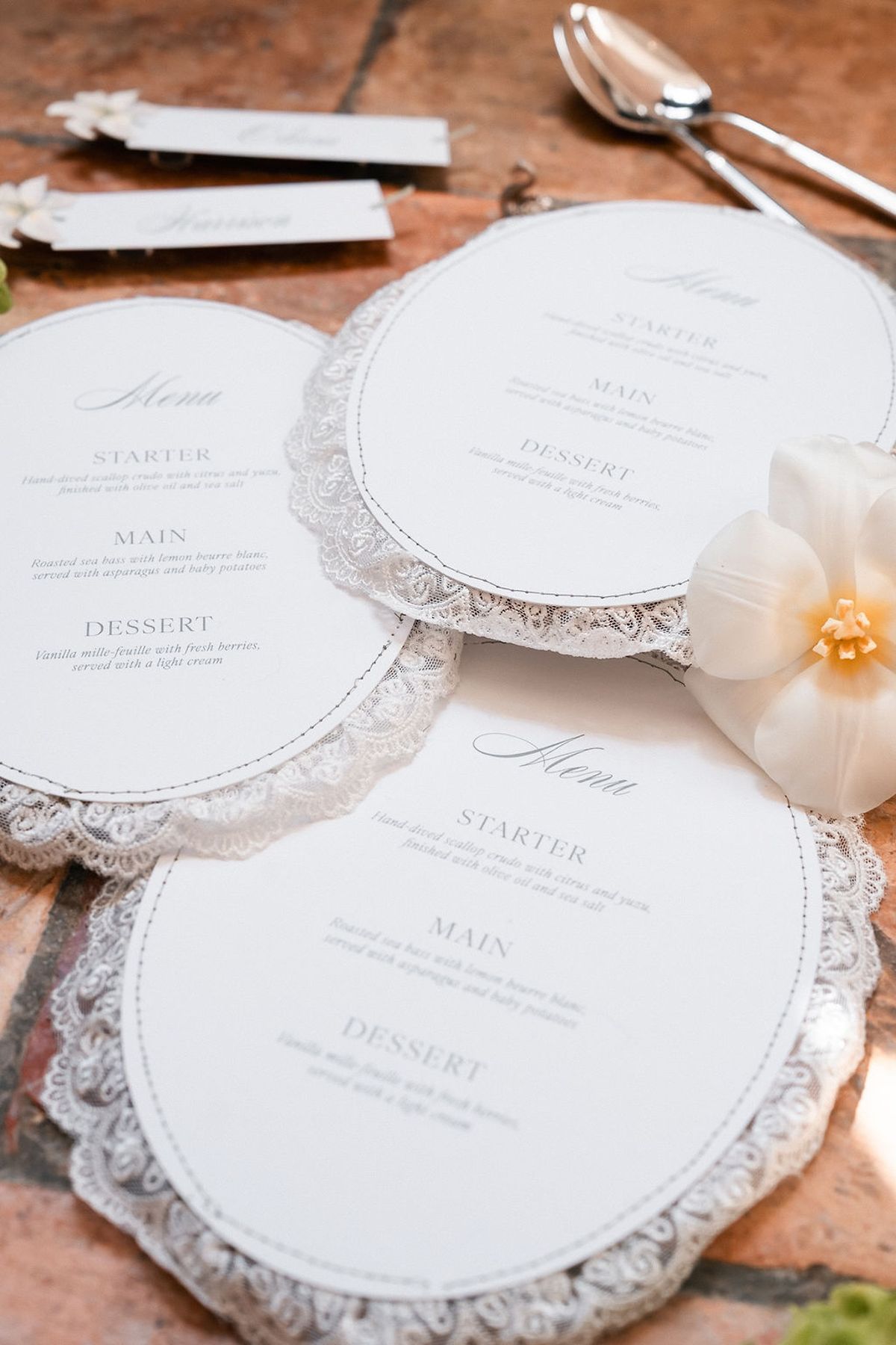 Round menu cards with scalloped lace edges arranged on a terracotta surface at Château de Sannes, Provence