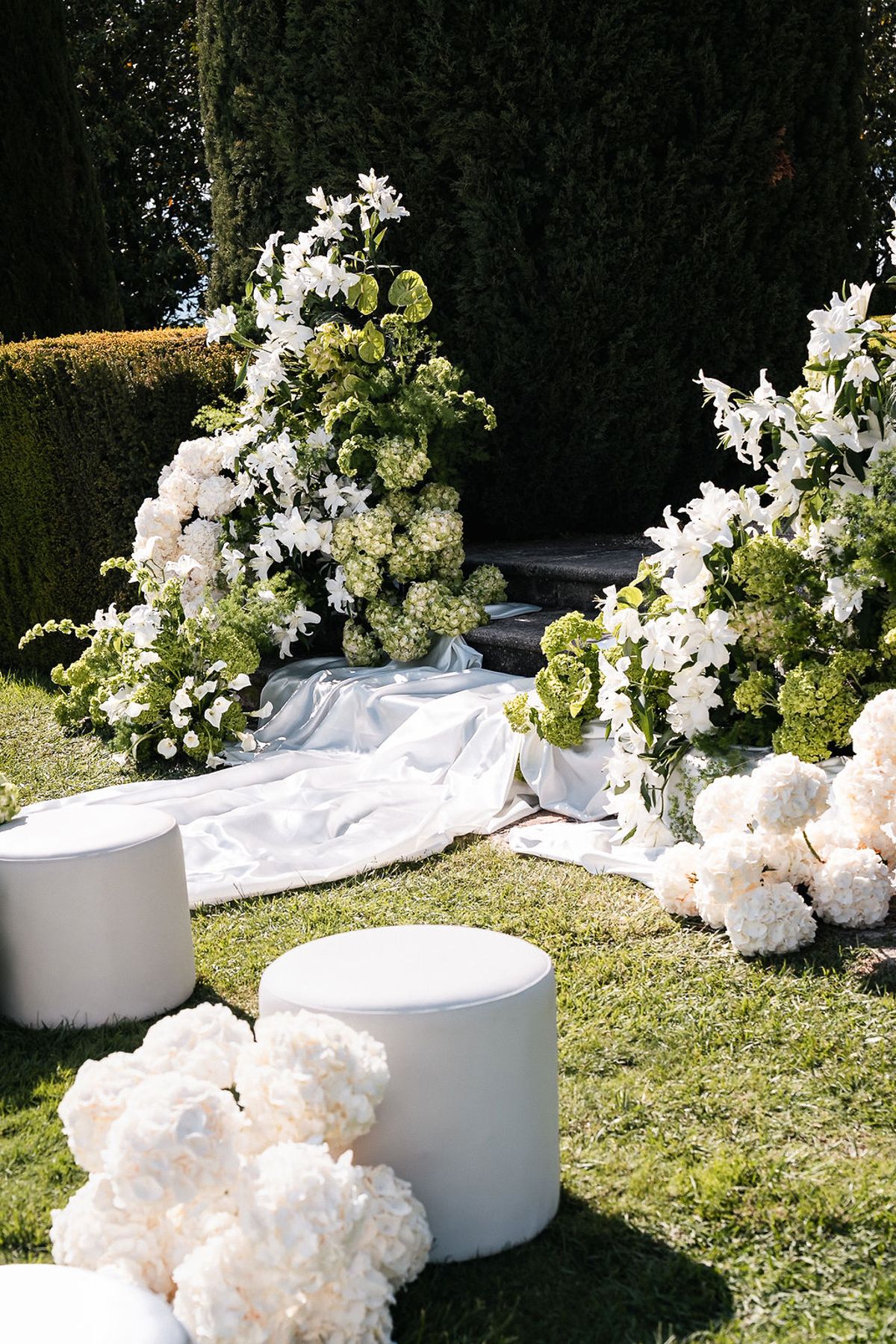 White floral installation, plinths and draped fabric marking the ceremony setting on the lawn at Château de Sannes, Provence