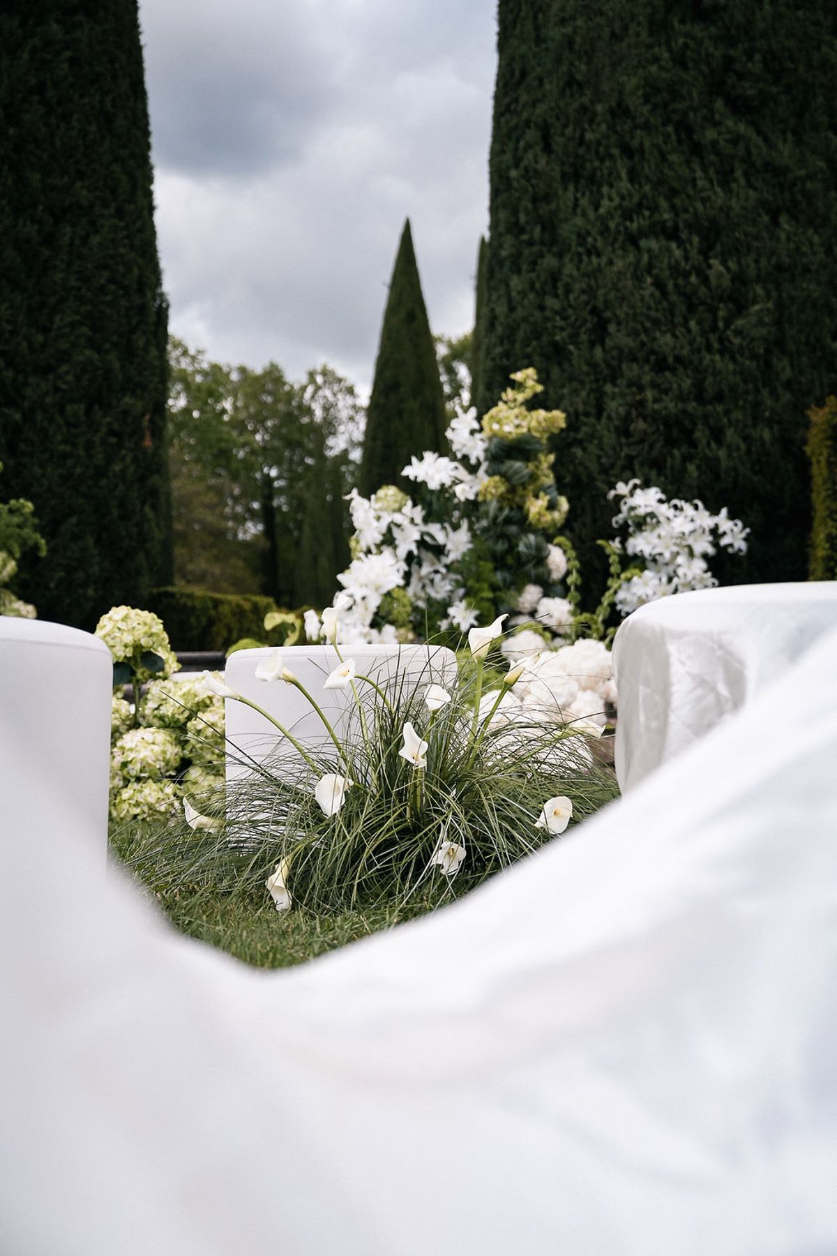 White floral installation with ornamental grasses and draped fabric on the ceremony lawn at Château de Sannes, Provence