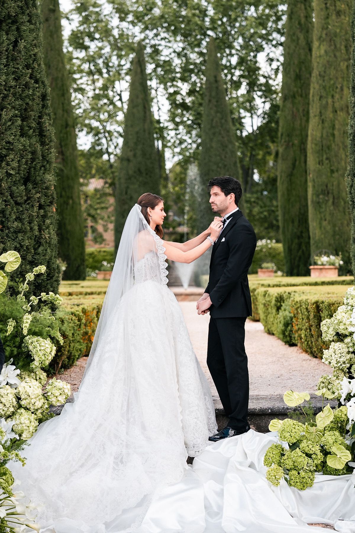 Bride in a full cathedral veil facing the groom among hydrangeas and clipped box at Château de Sannes, Provence