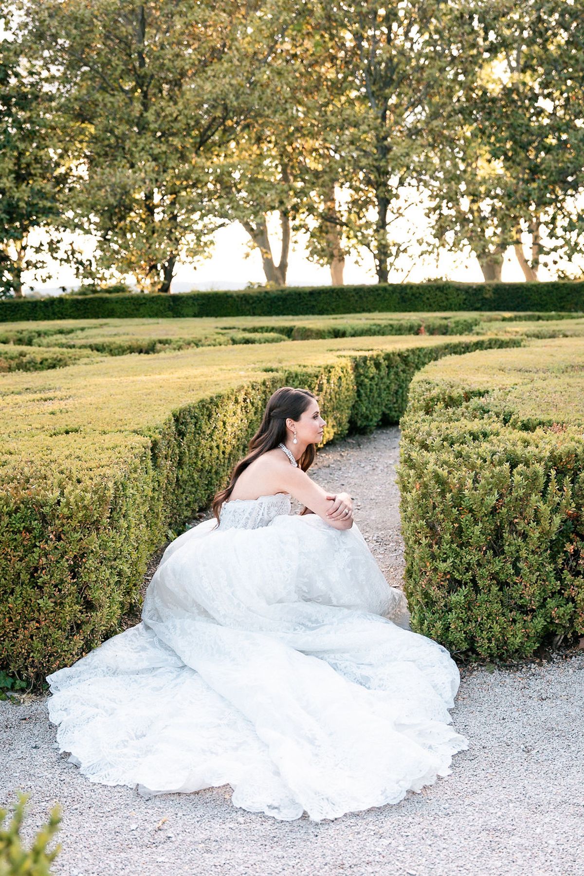 Bride seated on the gravel path amid the clipped box parterres at Château de Sannes, Provence