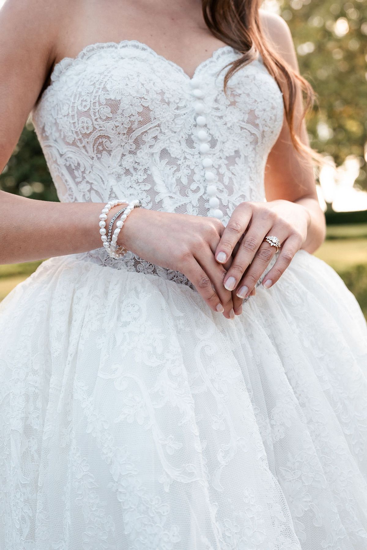 Close view of a lace corset bodice, pearl bracelets and a ring, worn with a full tulle skirt at Château de Sannes, Provence