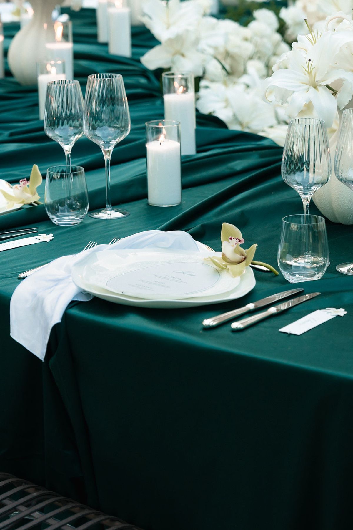 Place setting on deep green linen with a white napkin, cut-glass stemware and pillar candles at Château de Sannes, Provence