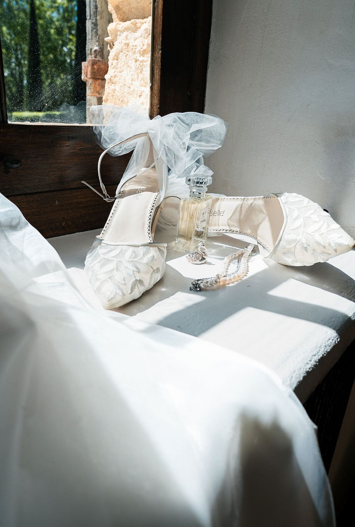 Bridal shoes, a garter and a champagne glass arranged on white bed linen at Château de Sannes, Provence