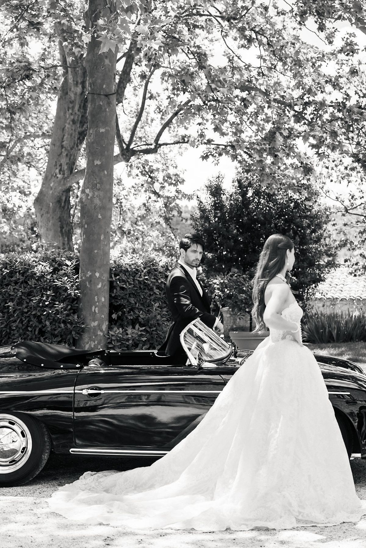 Black and white portrait of the bride and groom with the vintage open-top car at Château de Sannes, Provence