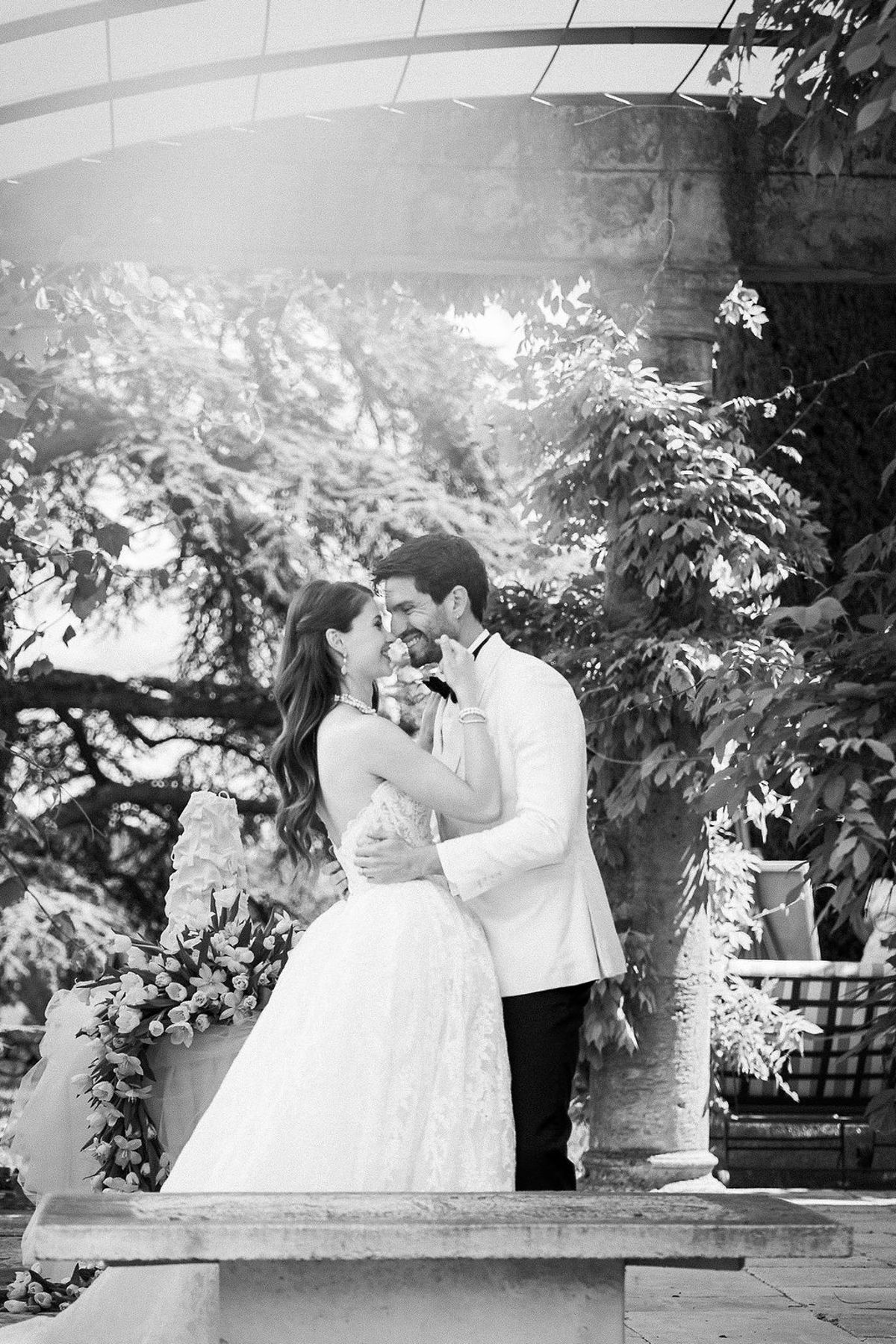 Black and white portrait of the bride and groom under the arcade among trailing foliage at Château de Sannes, Provence