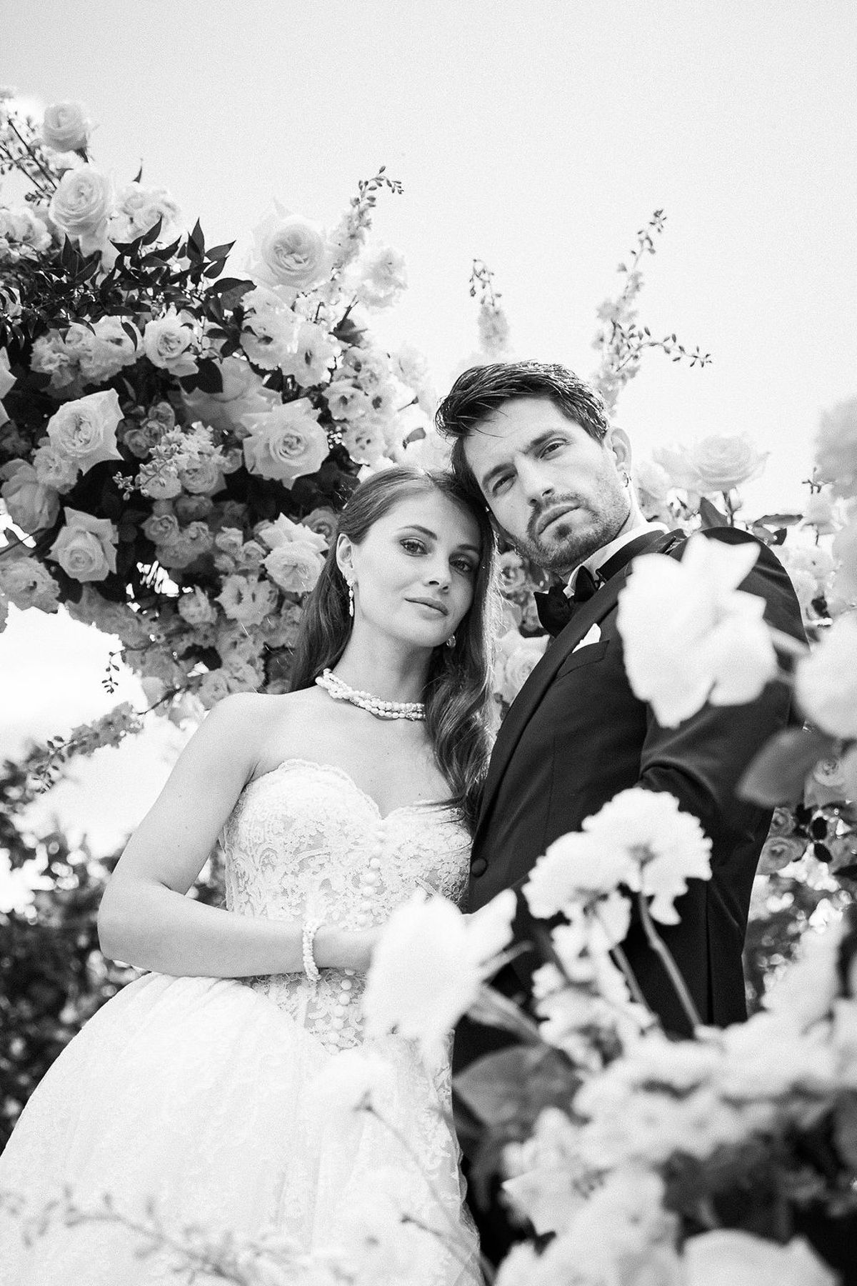 Black and white portrait of the bride and groom framed by white roses and lilies at Château de Sannes, Provence