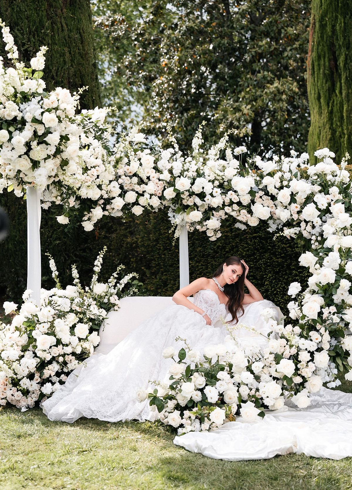 Bride reclining within the white floral ceremony installation at Château de Sannes, Provence