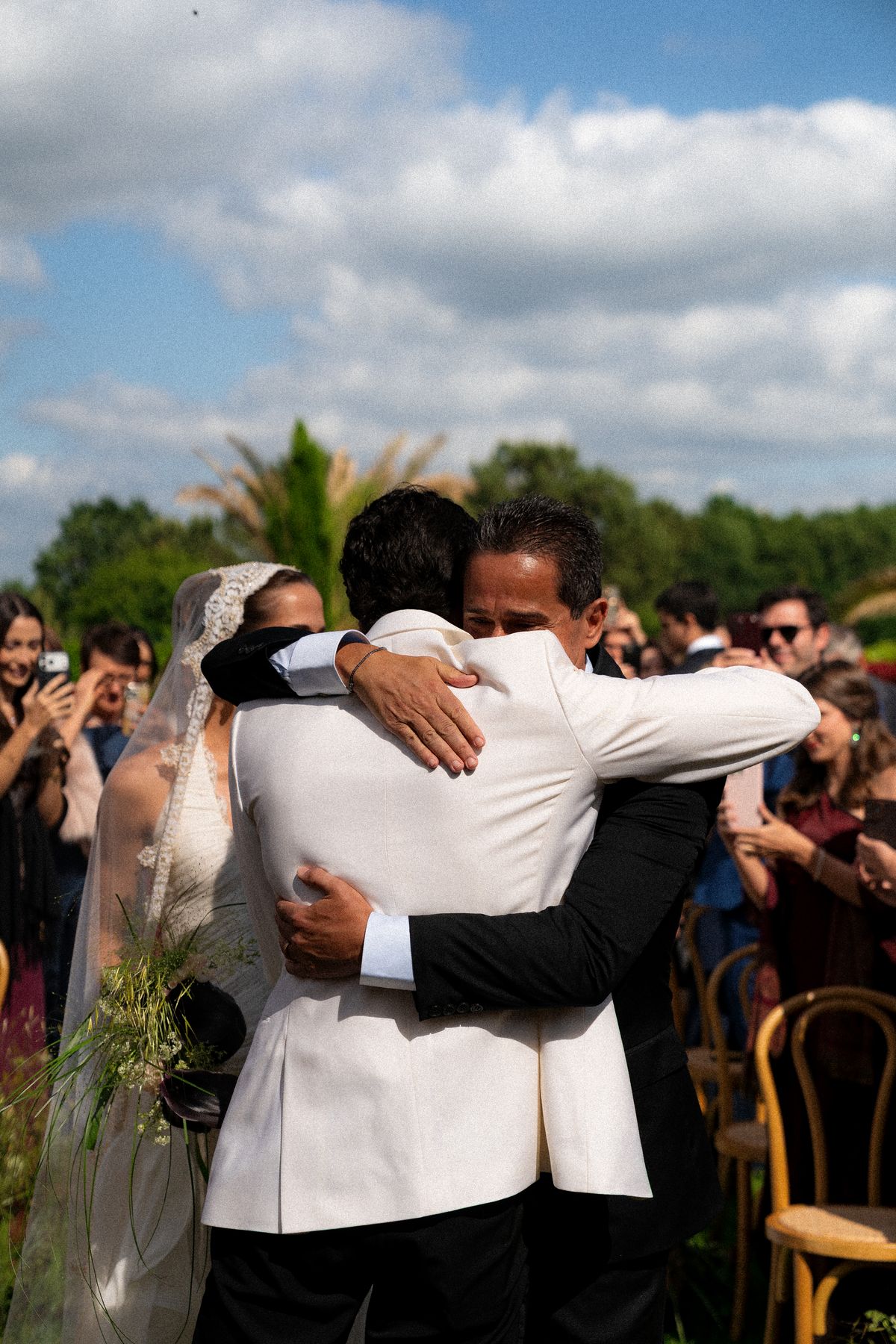 Isadora & Hugo — the groom embracing a guest as the bride looks on, spring wedding in Nouvelle-Aquitaine
