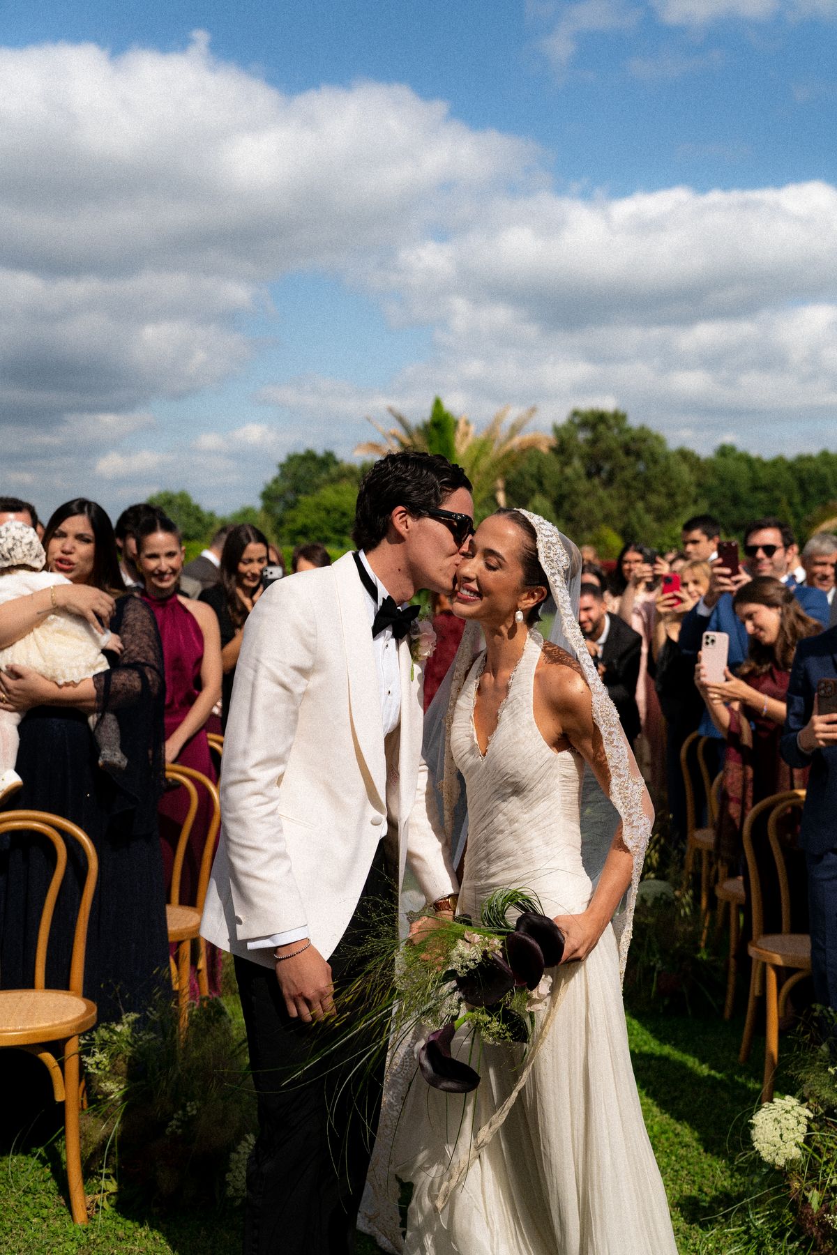 Isadora & Hugo — the couple kissing among the standing guests, spring wedding in Nouvelle-Aquitaine