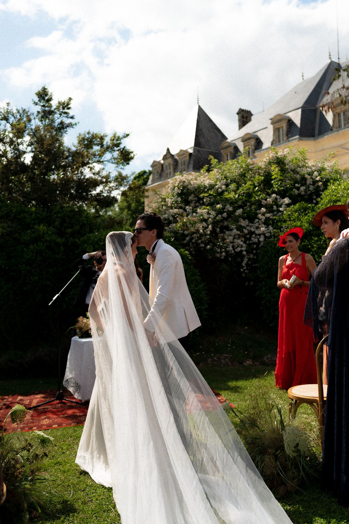 Isadora & Hugo — the bride at the ceremony table, her veil across the rug, spring wedding in Nouvelle-Aquitaine