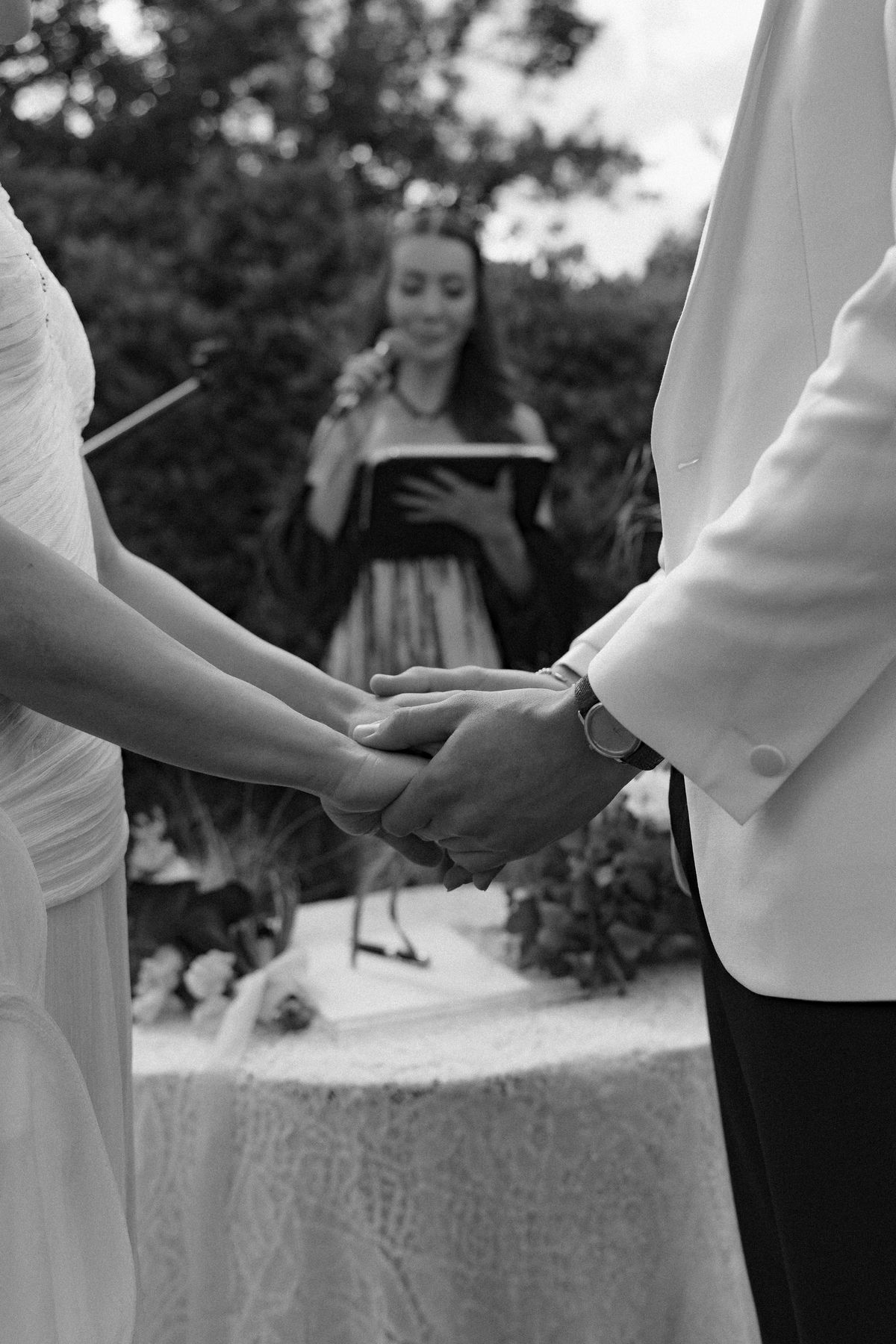 Isadora & Hugo — the couple's joined hands as the celebrant reads, spring wedding in Nouvelle-Aquitaine