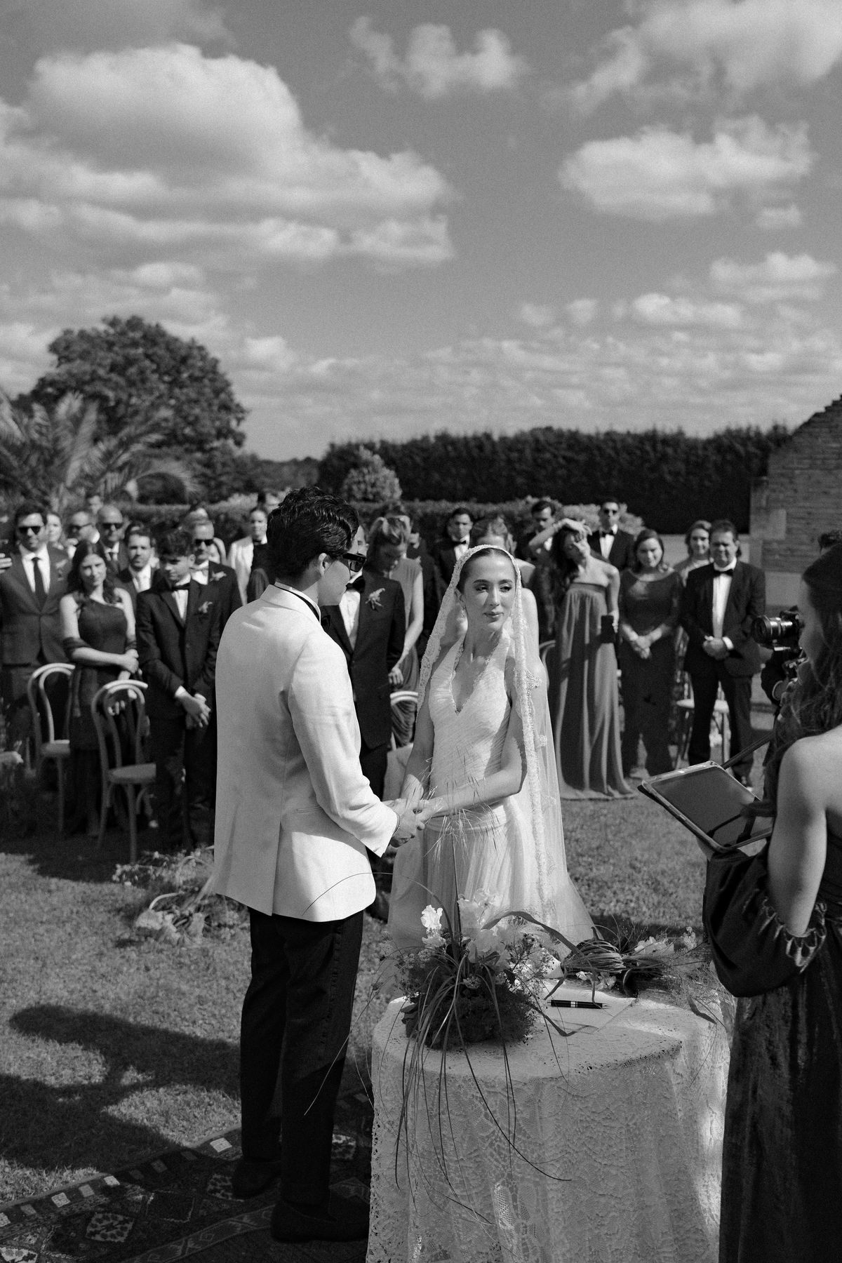 Isadora & Hugo — the couple at the ceremony table with guests beyond, spring wedding in Nouvelle-Aquitaine
