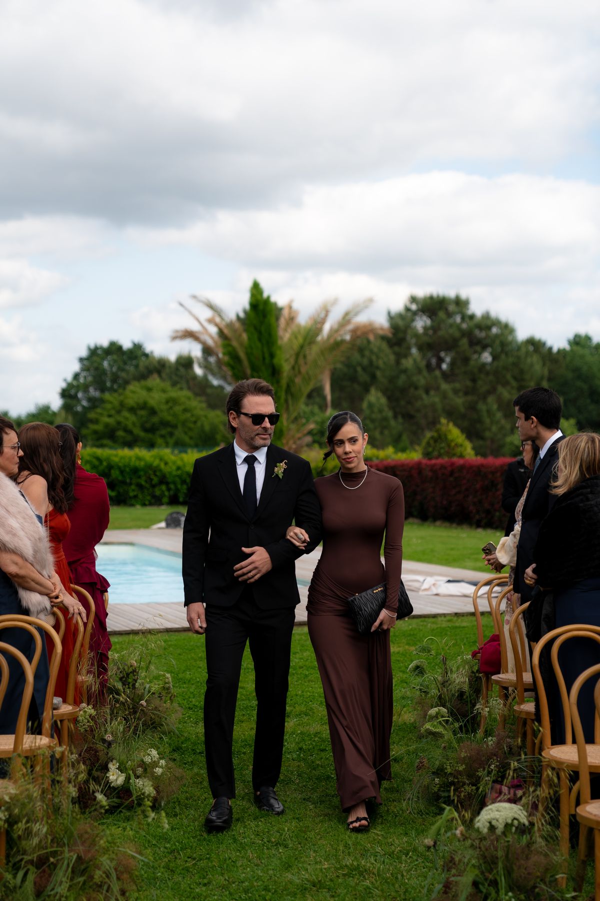 Isadora & Hugo — guests walking to their seats with the pool beyond, spring wedding in Nouvelle-Aquitaine