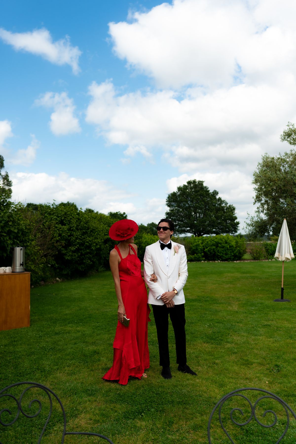 Isadora & Hugo — guests on the lawn, one in a red gown and wide-brimmed hat, spring wedding in Nouvelle-Aquitaine