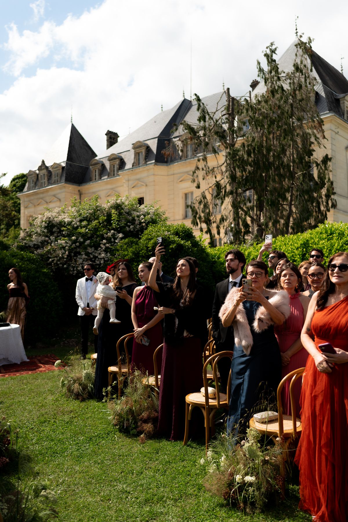 Isadora & Hugo — guests watching the ceremony with the chateau behind, spring wedding in Nouvelle-Aquitaine