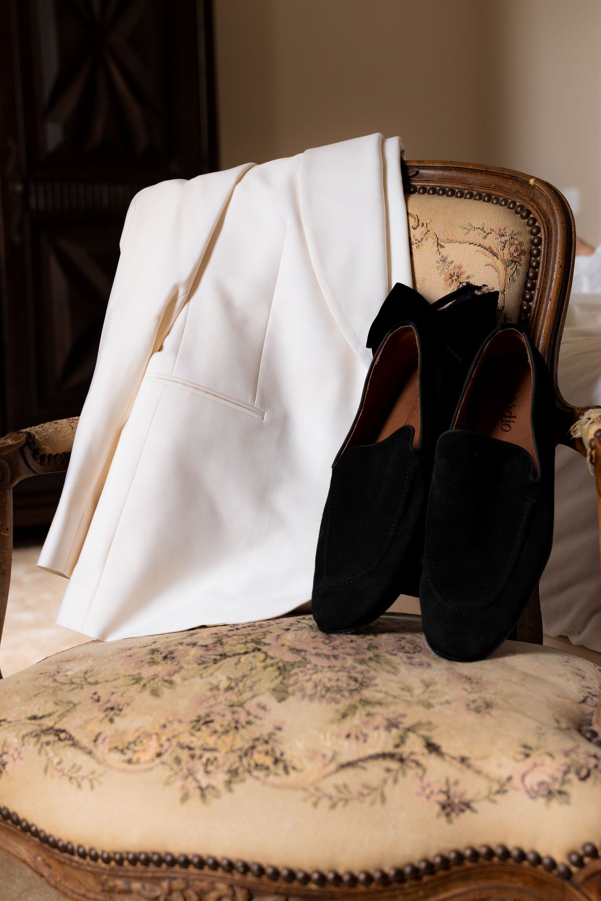 Isadora & Hugo — the groom's white dinner jacket and shoes laid on a chair, spring wedding in Nouvelle-Aquitaine