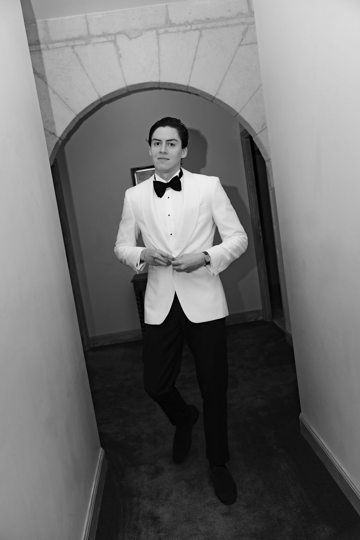 Isadora & Hugo — the groom in a doorway in his white dinner jacket, spring wedding in Nouvelle-Aquitaine