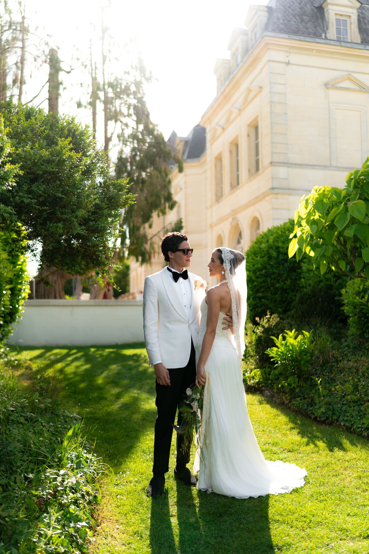 Isadora & Hugo — the couple in the garden beside the chateau wall, spring wedding in Nouvelle-Aquitaine