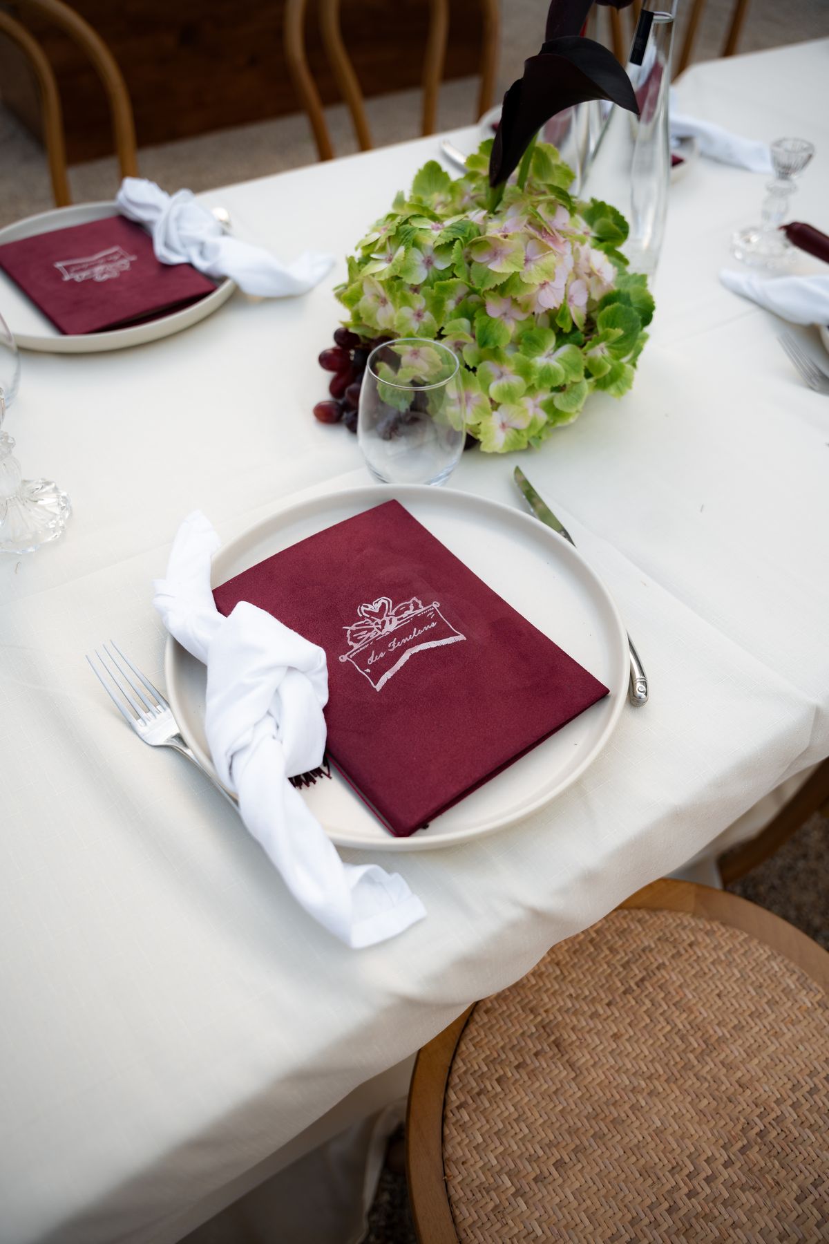 Isadora & Hugo — a place setting with a burgundy menu and a posy of green blooms, spring wedding in Nouvelle-Aquitaine