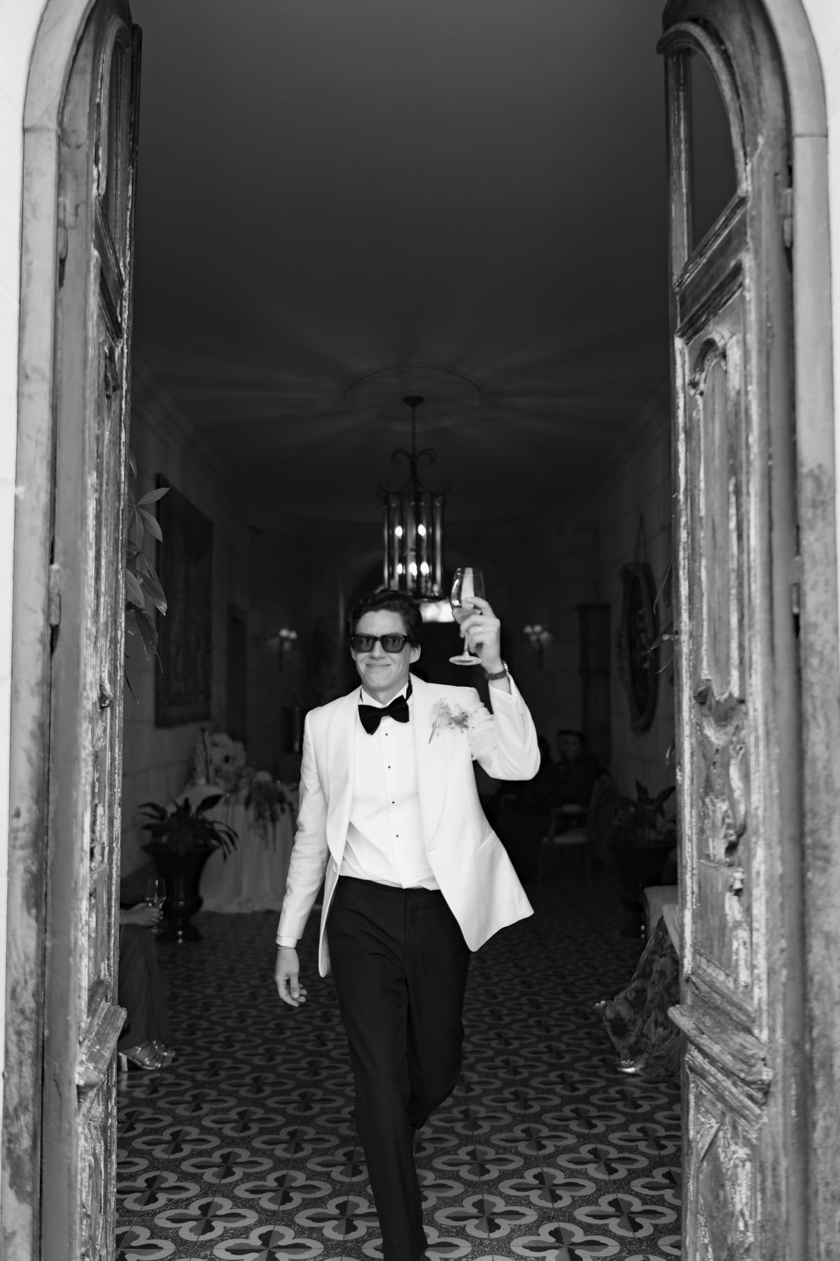 Isadora & Hugo — the groom in his white dinner jacket in a doorway, spring wedding in Nouvelle-Aquitaine