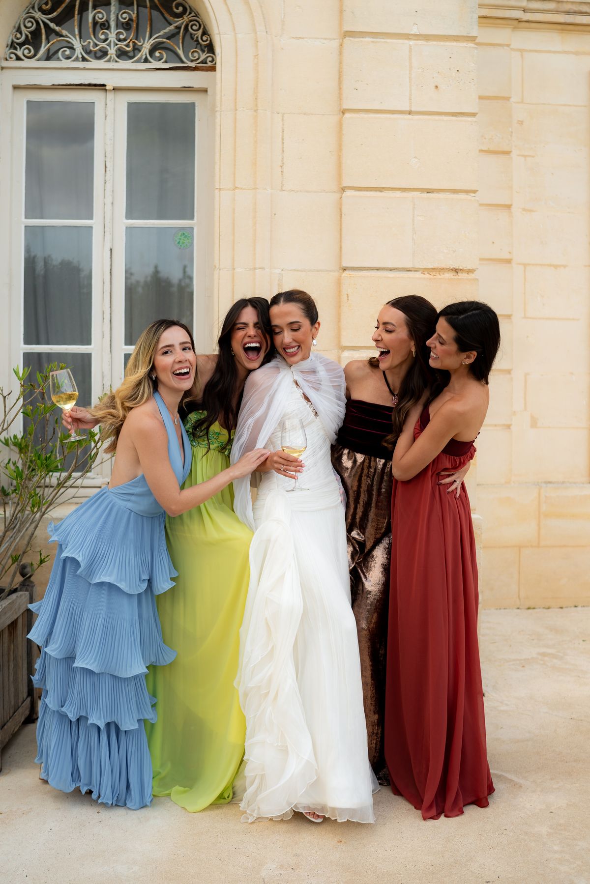 Isadora & Hugo — the bride with four guests in coloured gowns outside the chateau, spring wedding in Nouvelle-Aquitaine