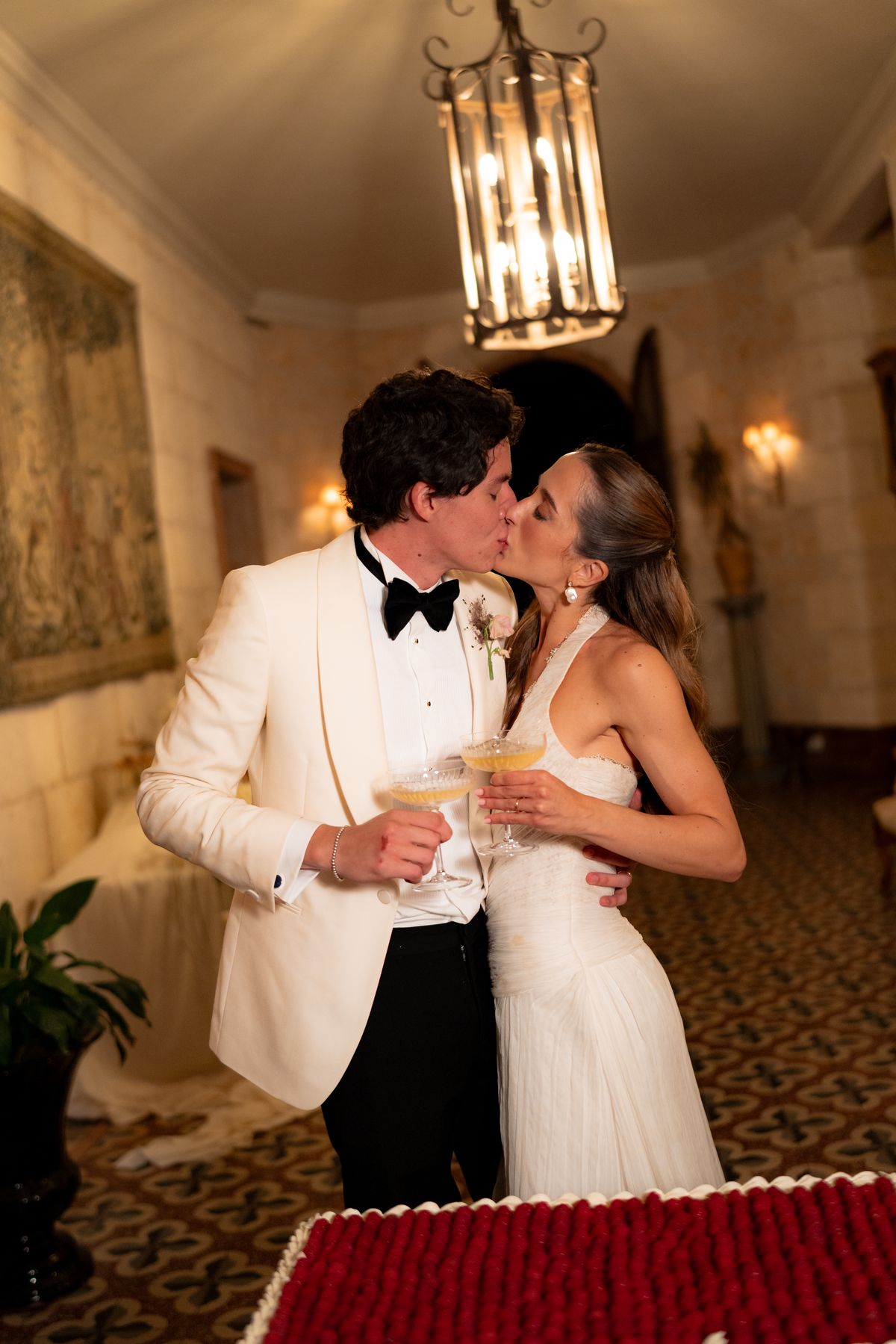 Isadora & Hugo — the couple with champagne beside the raspberry-topped cake, spring wedding in Nouvelle-Aquitaine