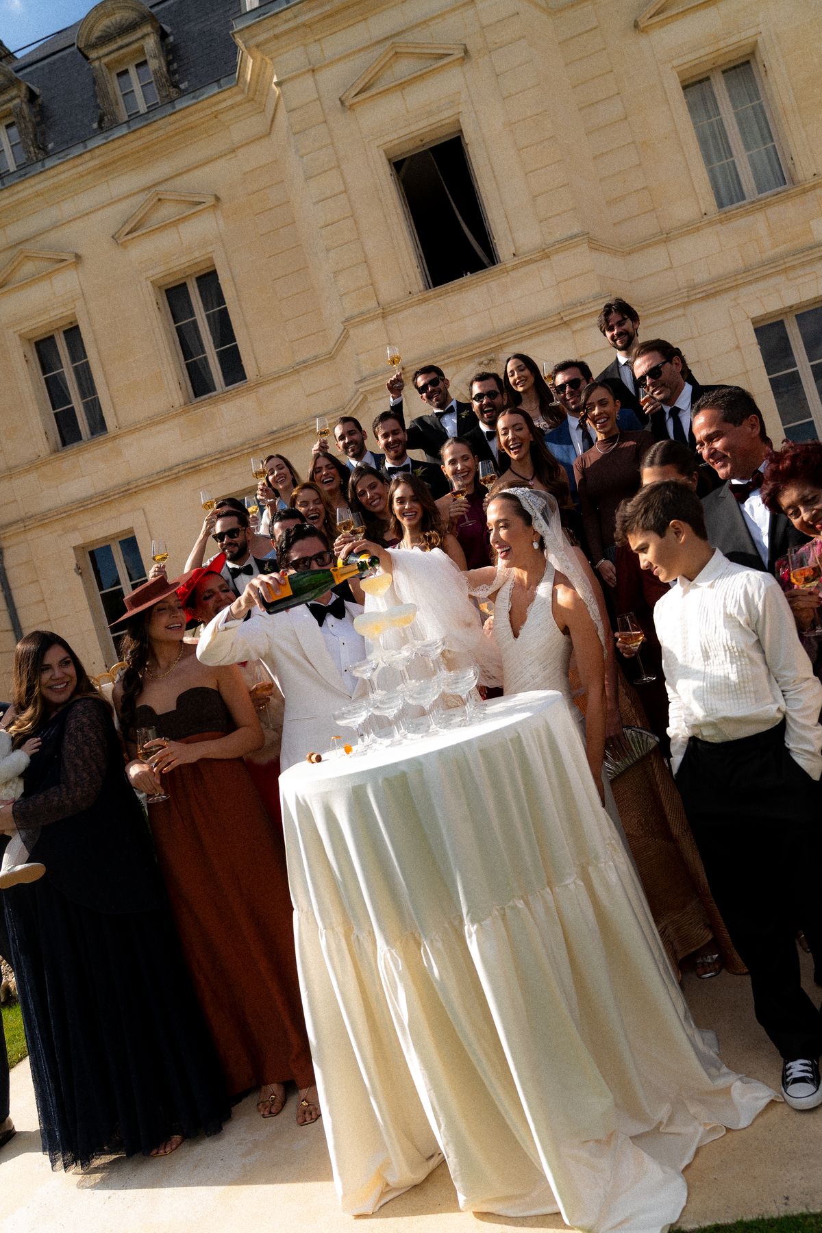 Isadora & Hugo — guests cheering from the chateau steps, spring wedding in Nouvelle-Aquitaine