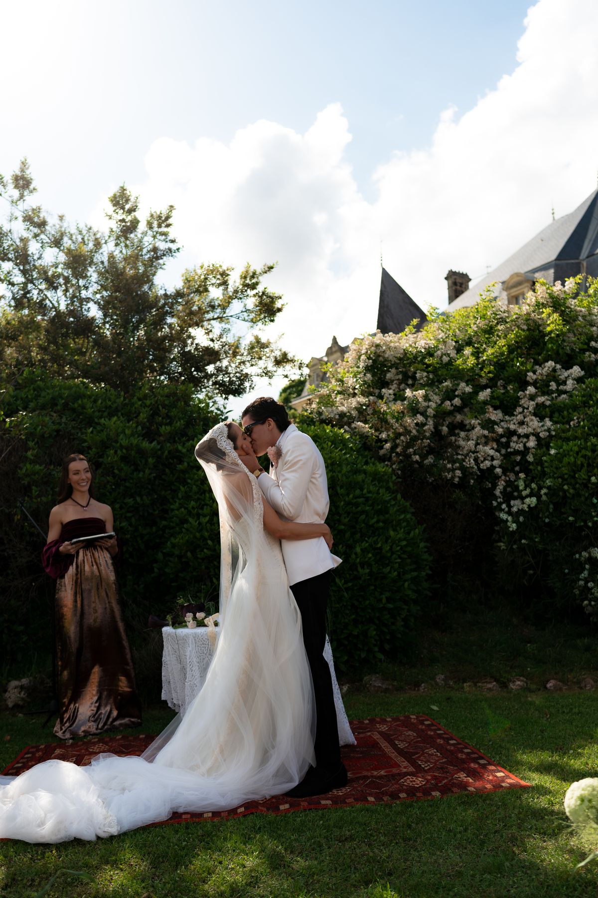 Isadora & Hugo — the couple embracing in the garden with the chateau behind, spring wedding in Nouvelle-Aquitaine