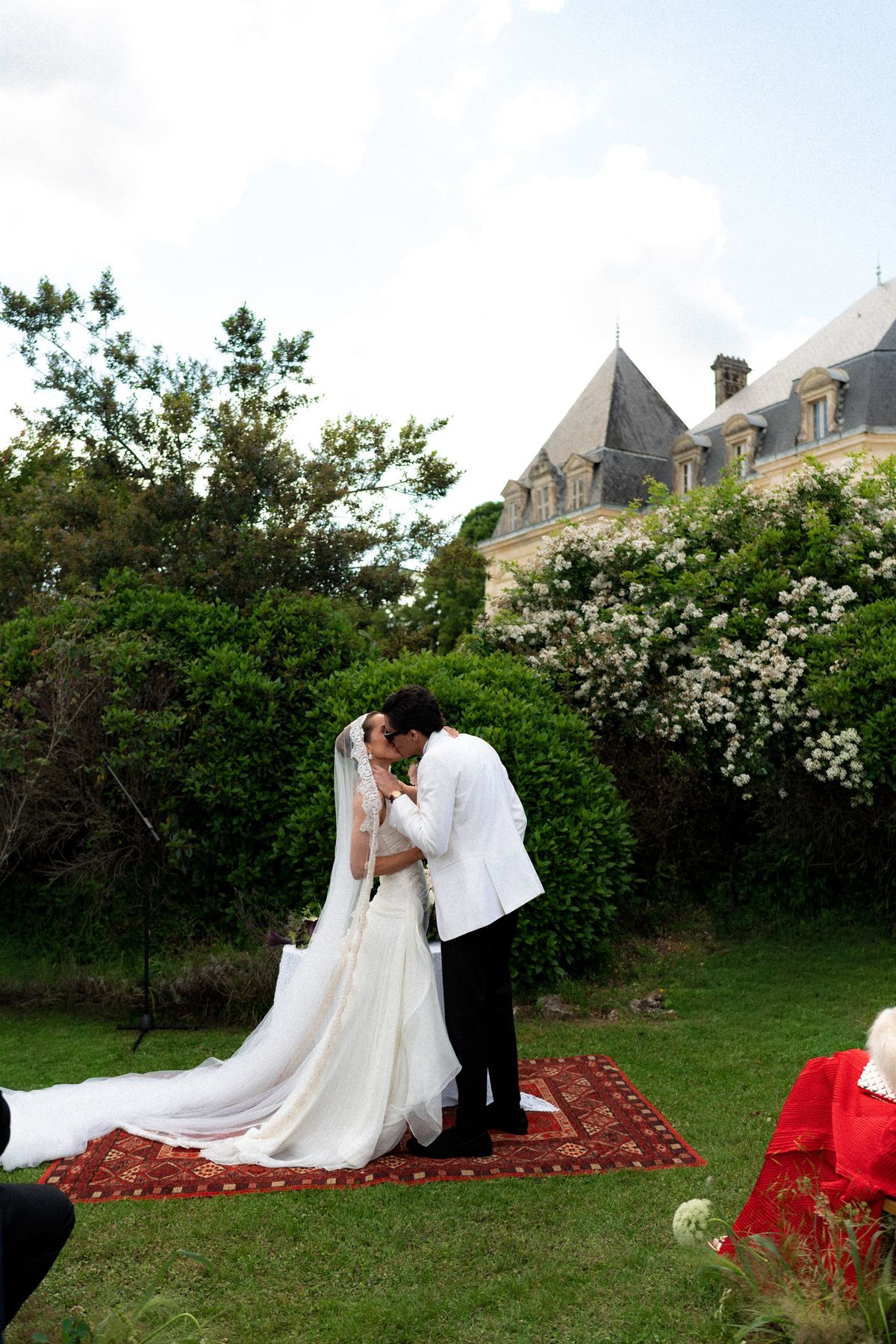 Isadora & Hugo — the couple embracing on a patterned rug in the garden, spring wedding in Nouvelle-Aquitaine
