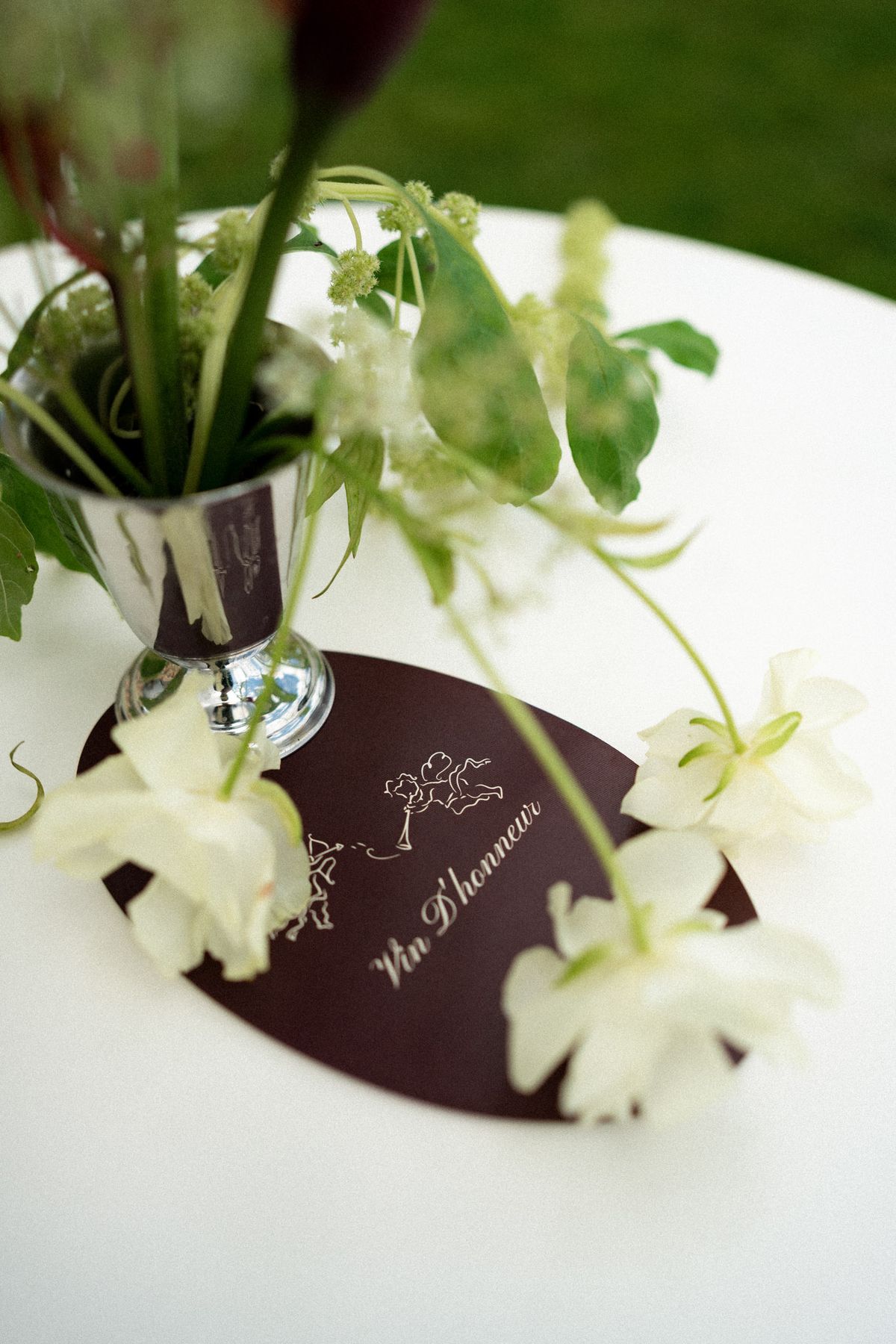 Isadora & Hugo — a place setting with white blooms in a silver vase and a burgundy menu card, spring wedding in Nouvelle-Aquitaine