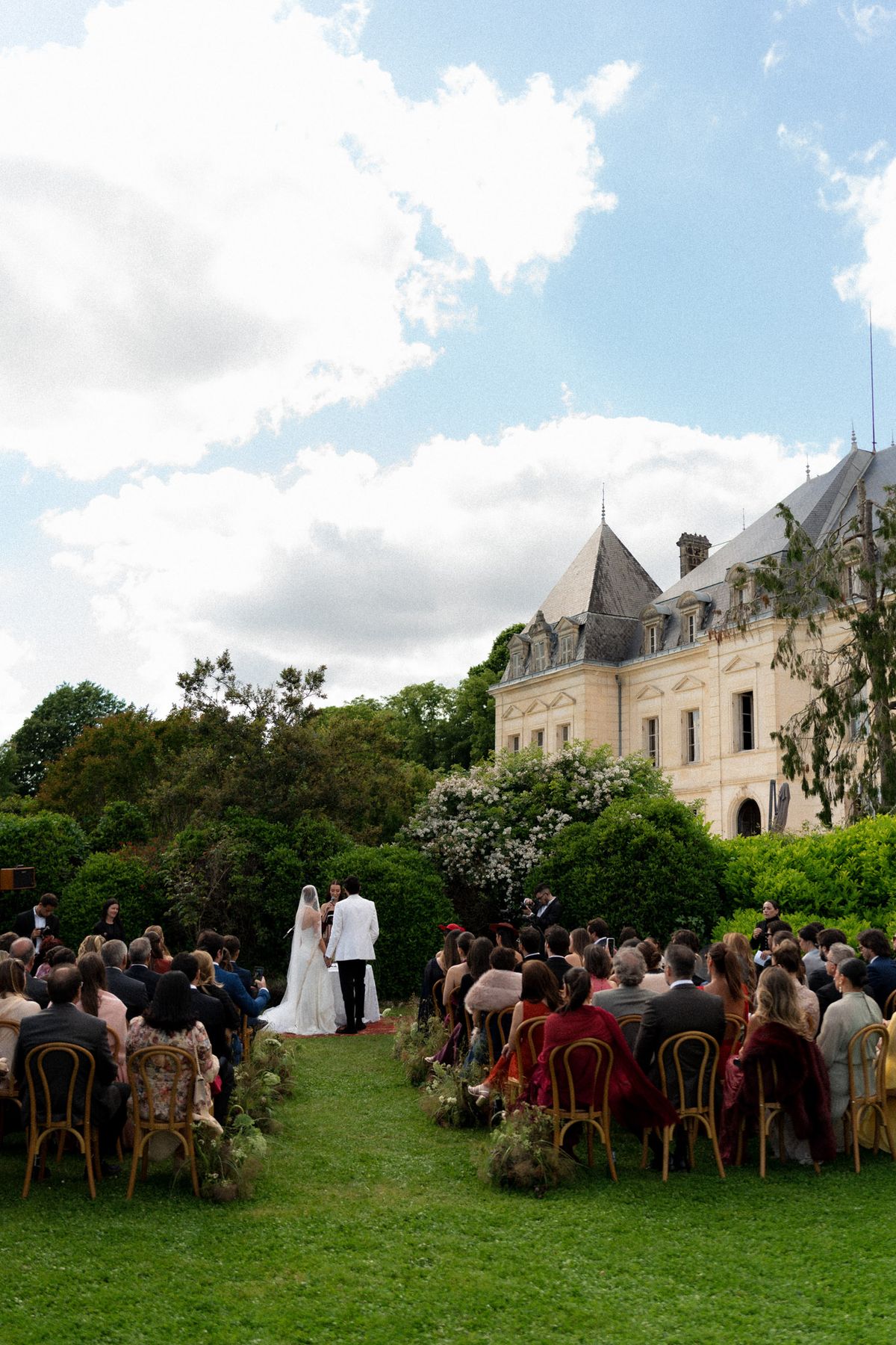 Isadora & Hugo — guests seated in rows on the lawn facing the chateau for the ceremony, spring wedding in Nouvelle-Aquitaine