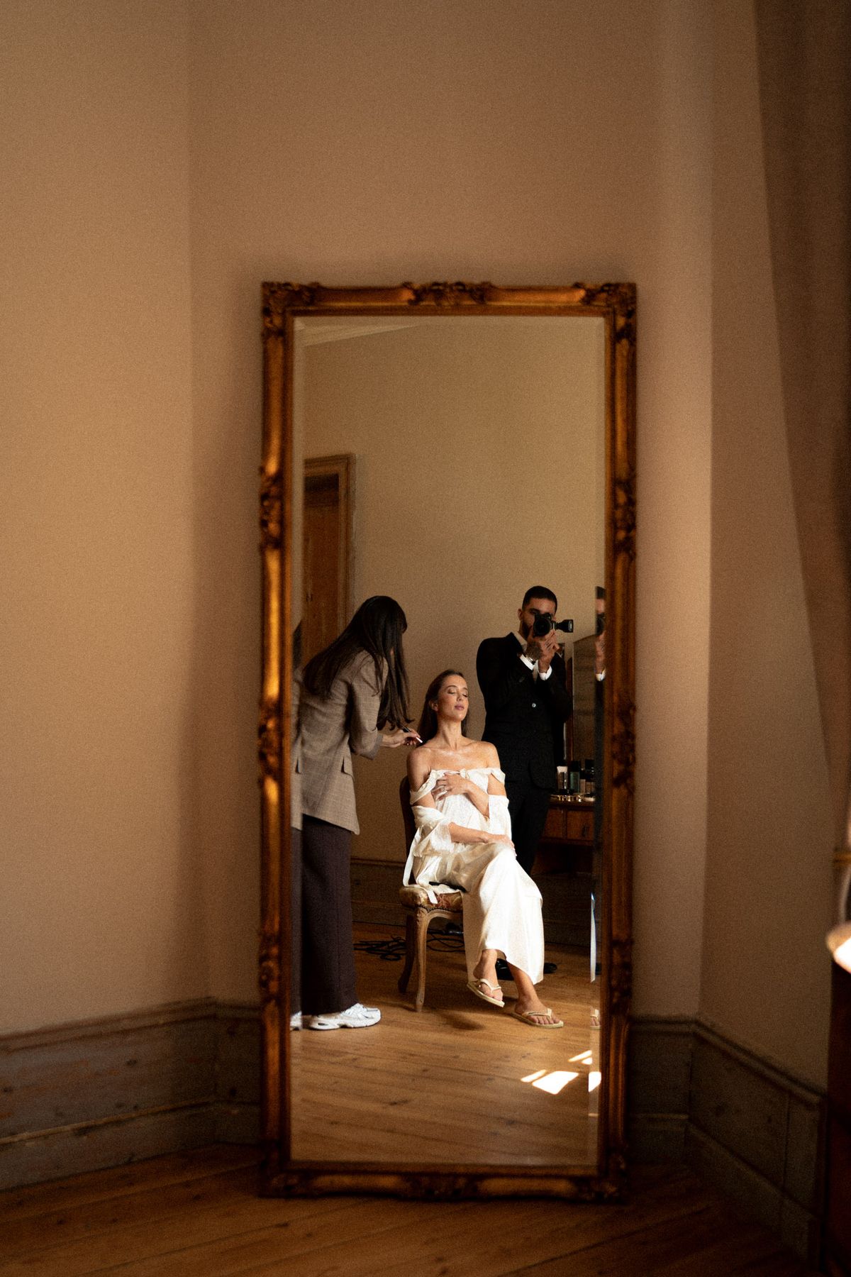 Isadora & Hugo — the bride reflected in a tall gilt mirror as she prepares, spring wedding in Nouvelle-Aquitaine