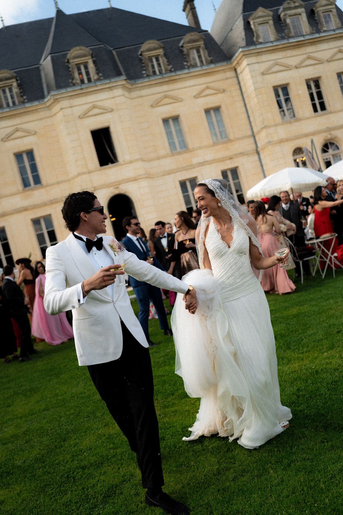 Isadora & Hugo — the couple hand in hand on the lawn as seated guests applaud, spring wedding in Nouvelle-Aquitaine