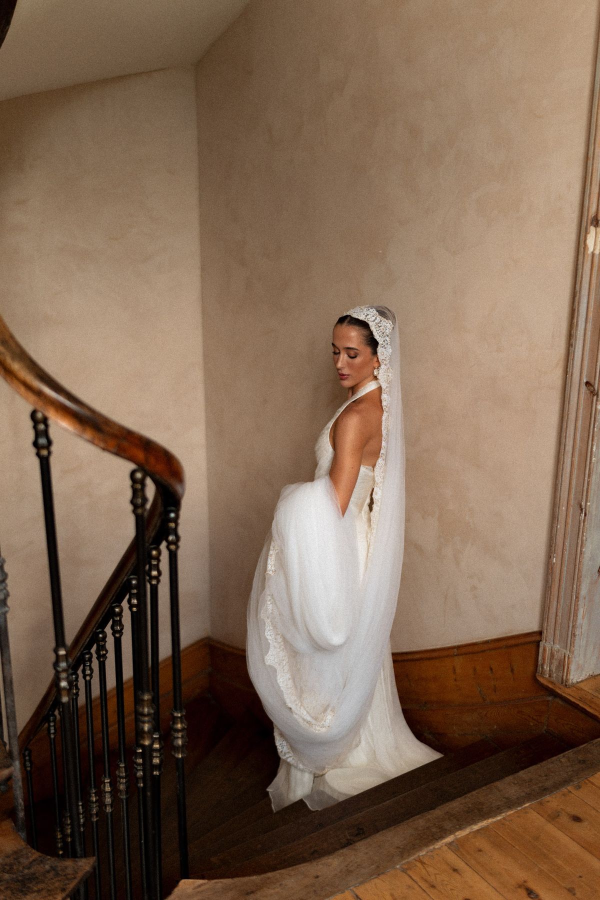 Isadora & Hugo — the bride on the chateau staircase in her ivory gown, veil falling behind her, spring wedding in Nouvelle-Aquitaine
