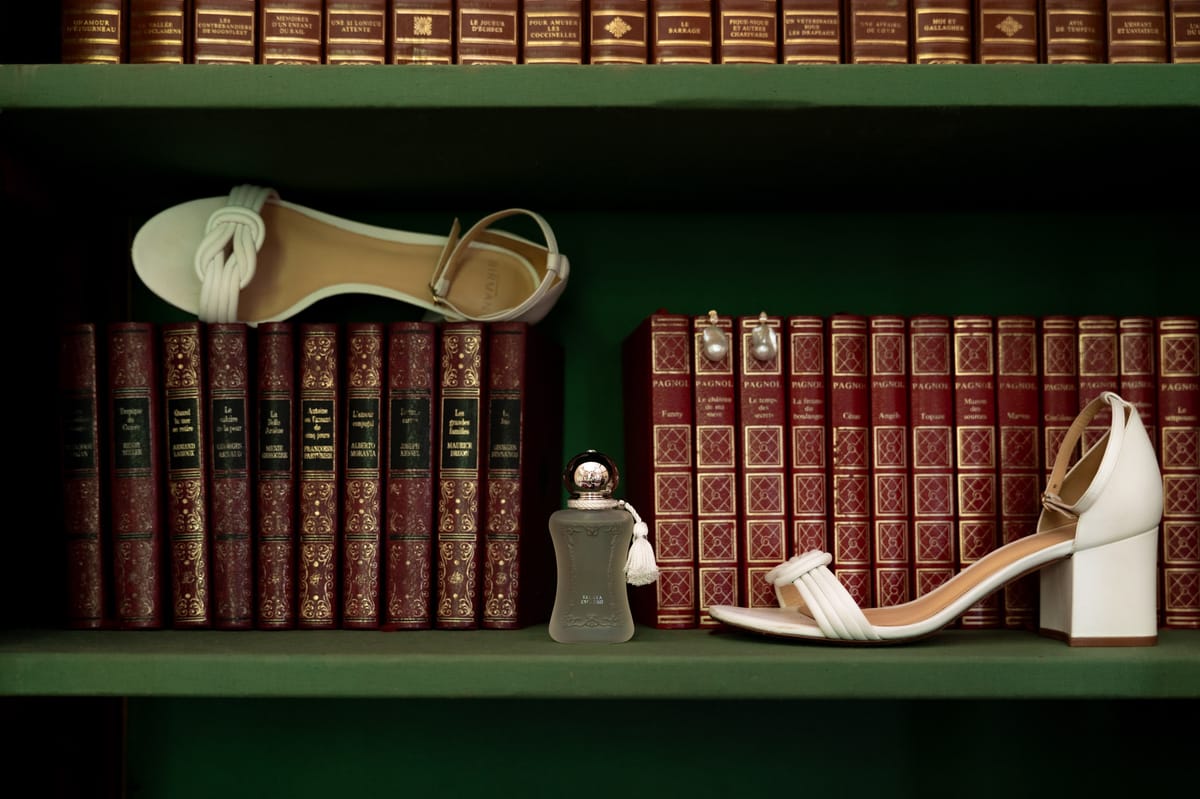 Isadora & Hugo — the bride's ivory heels and a bottle of perfume arranged on a green shelf beside red leather-bound books, spring wedding in Nouvelle-Aquitaine