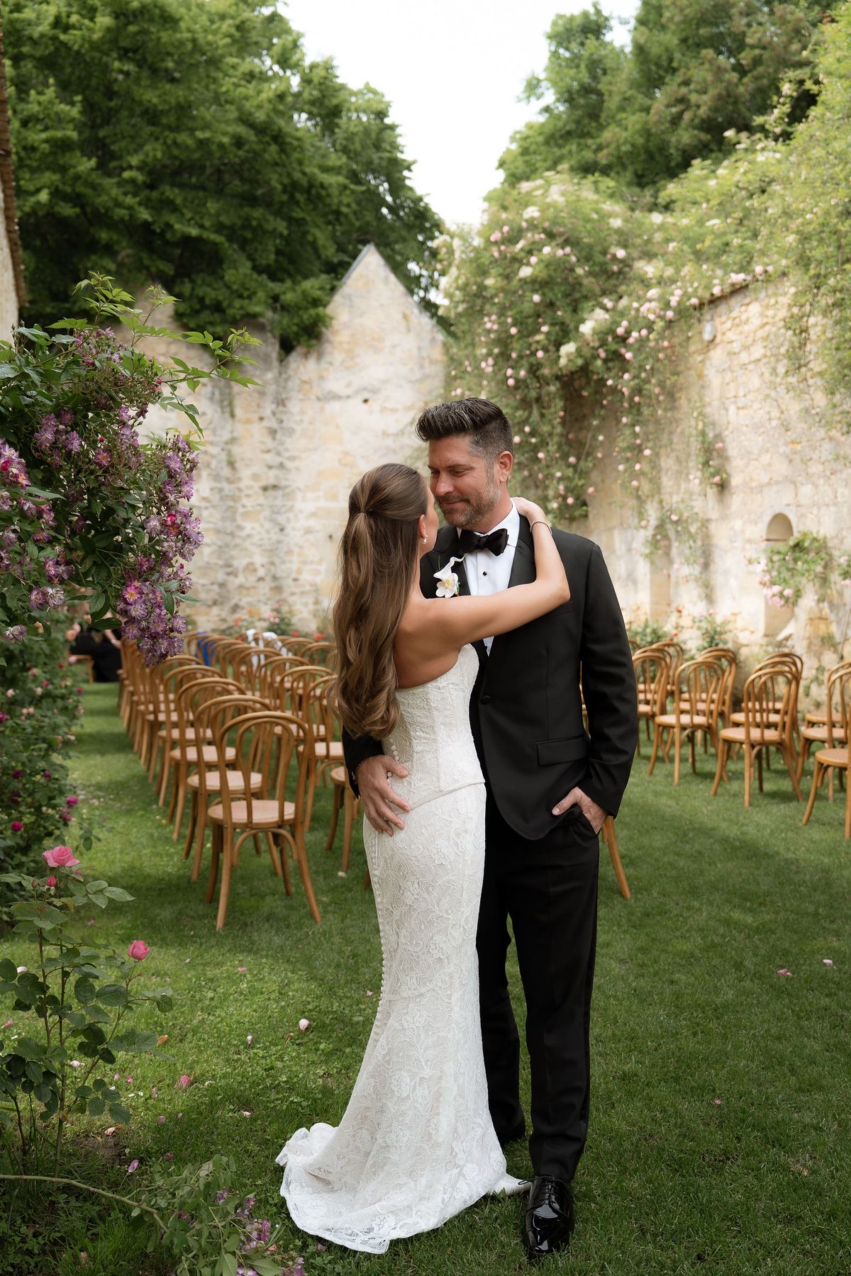 Jori and JD walking together past climbing roses on a stone wall