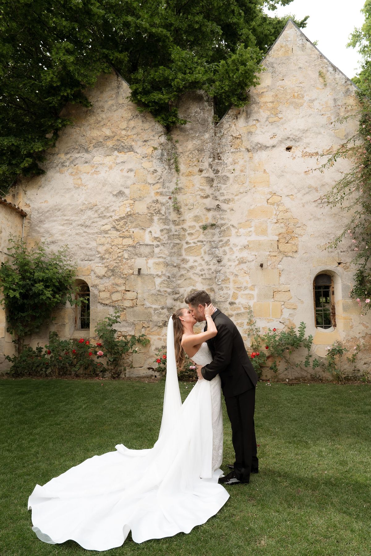 Jori and JD kissing on the lawn in front of the château