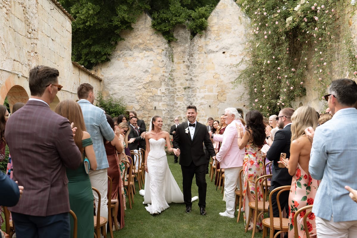 Jori and JD walking back down the aisle past seated guests