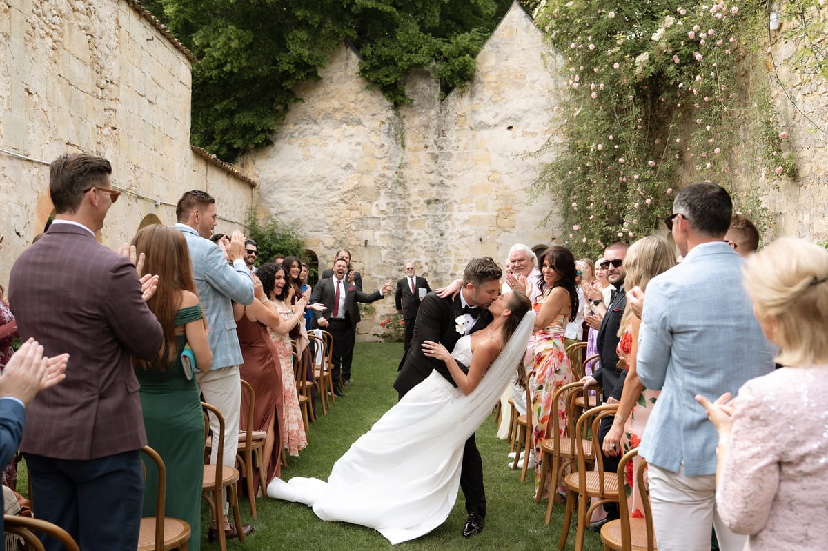 Jori and JD kissing as guests look on after the ceremony