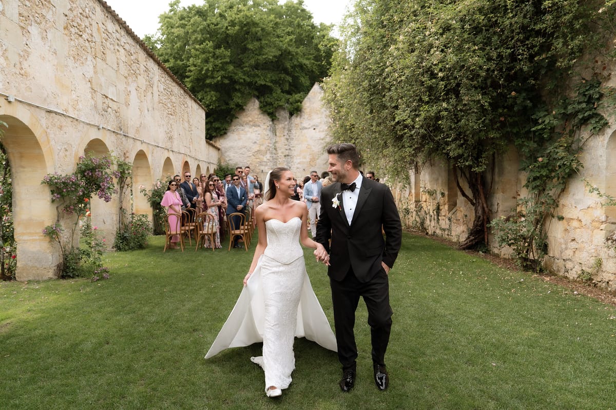 Jori and JD walking together with guests seated behind them