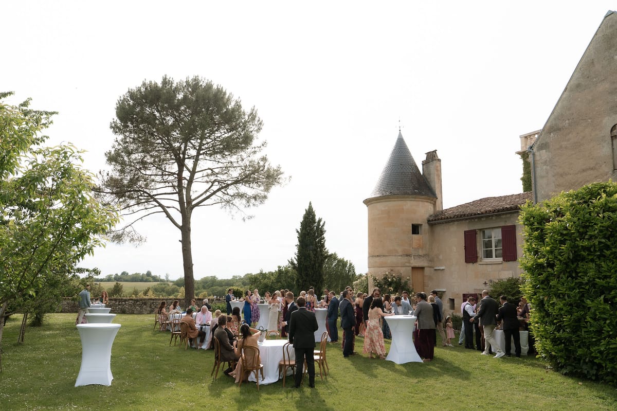 Guests gathered at high cocktail tables beneath the trees