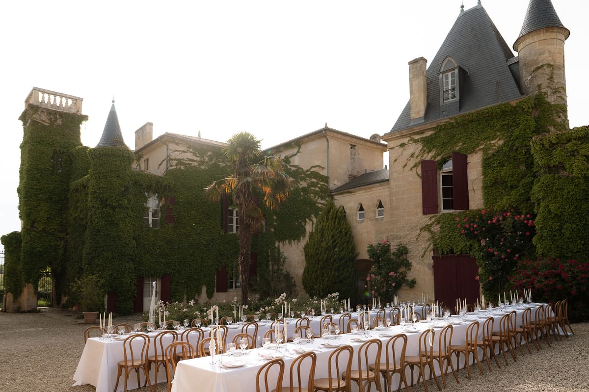 A long reception table set with bentwood chairs on the château's gravel courtyard