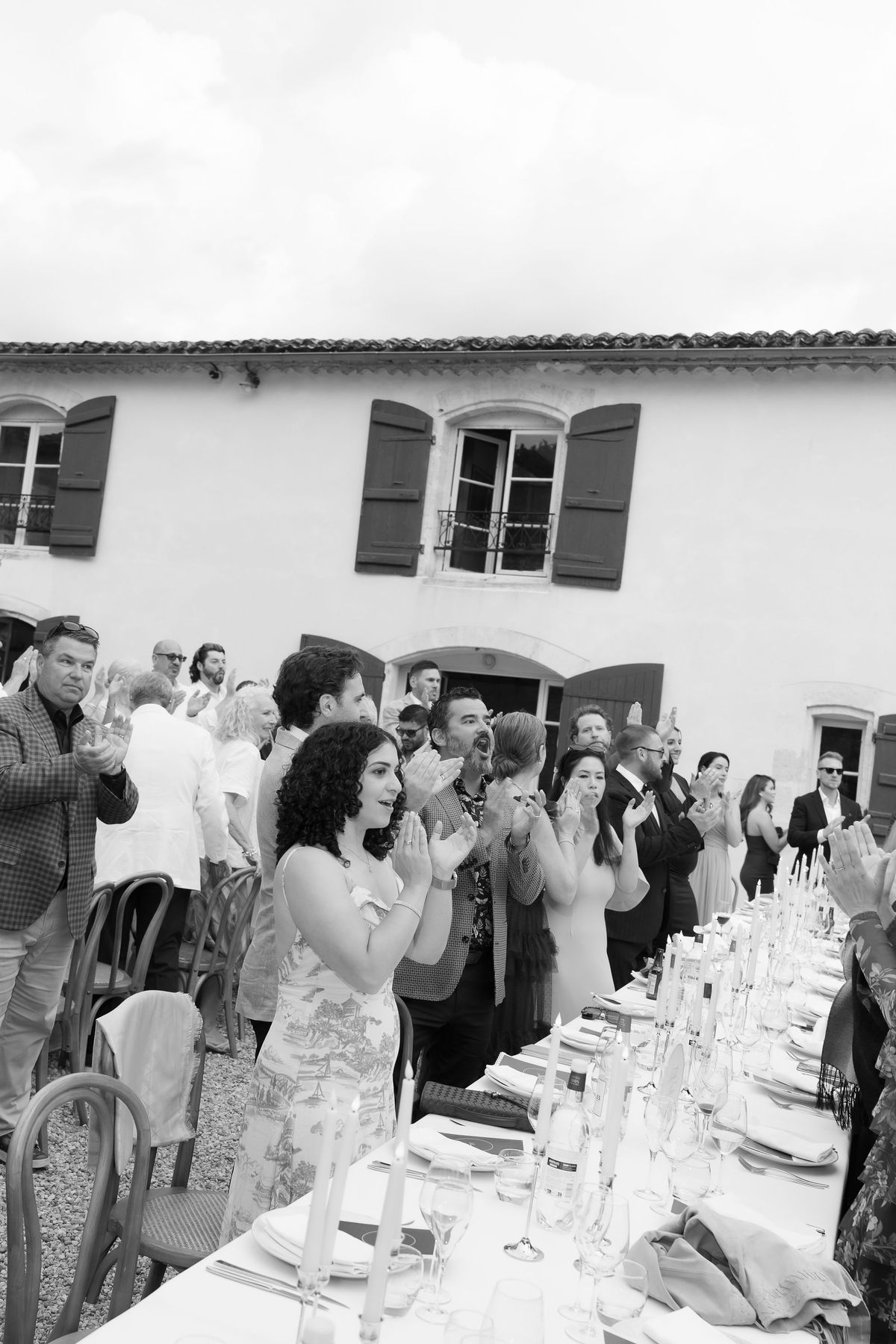 A black-and-white photo of guests clapping at the reception table