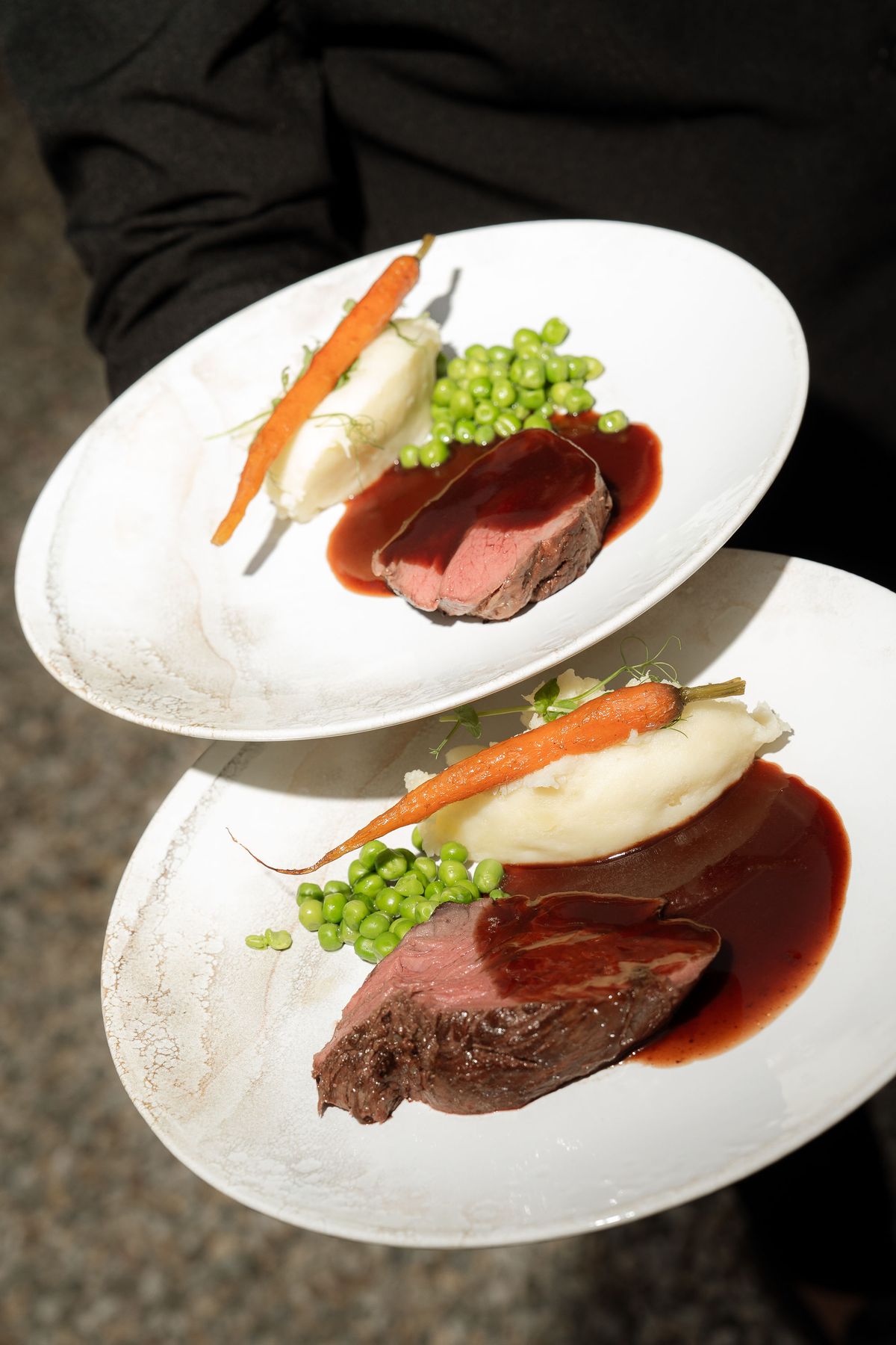 A plated main course being carried to the reception table