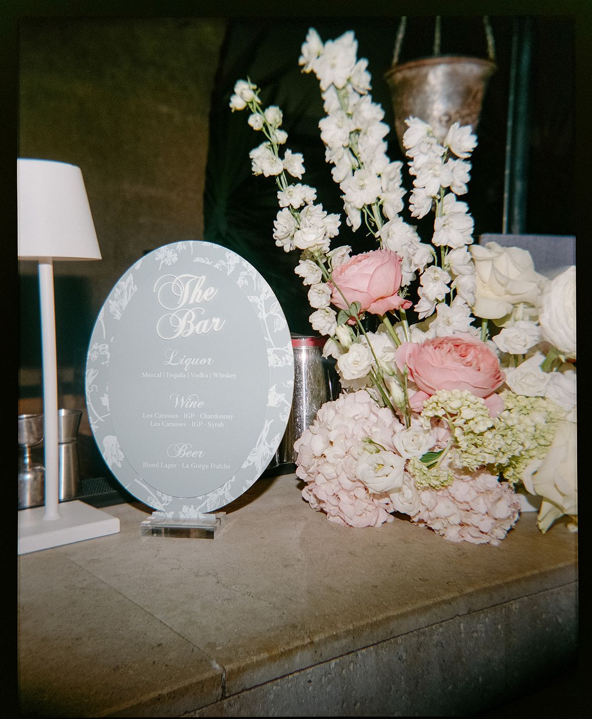 A round bar menu sign beside pink and white flowers and delphinium
